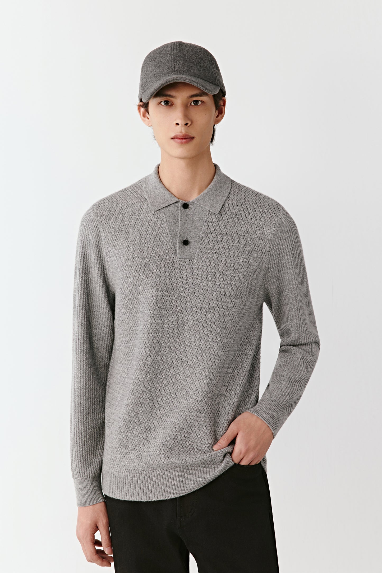 Man wearing a gray patterned sweater and cap on a white background