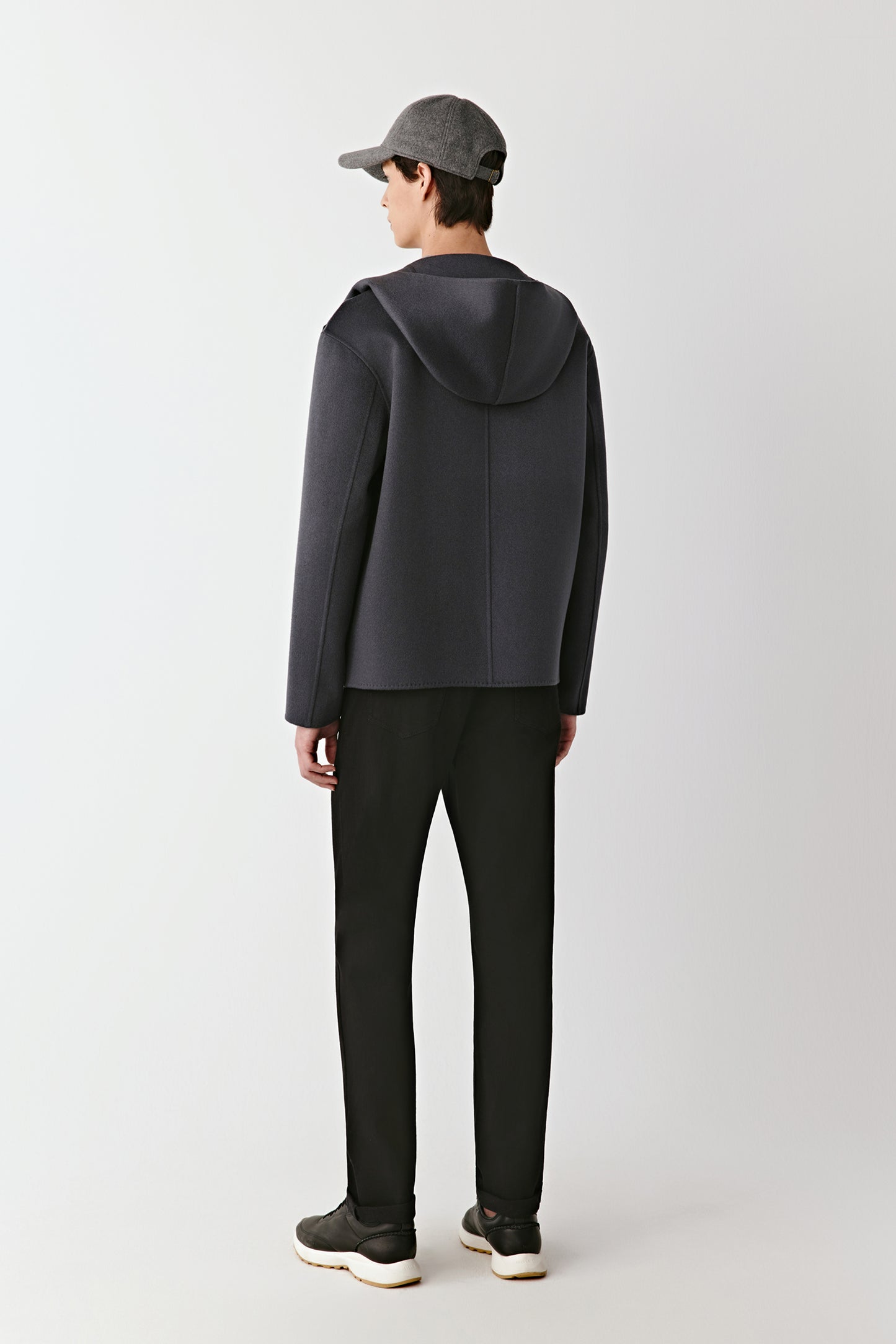 Men wearing a dark gray hoodie and pants with a cap on a white background