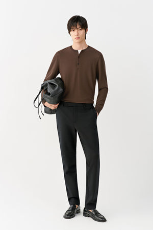 Front view of a man wearing deep black slim-leg wool trousers, showing the streamlined silhouette and mid-rise waist.
