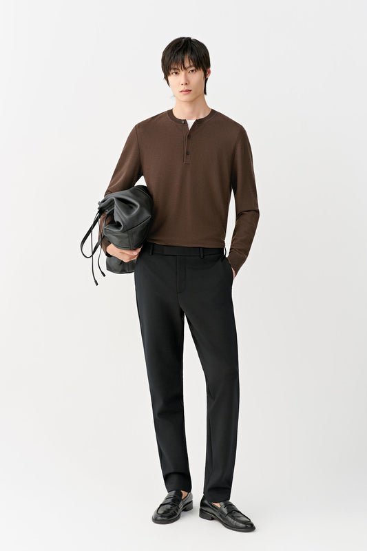 Front view of a man wearing deep black slim-leg wool trousers, showing the streamlined silhouette and mid-rise waist.