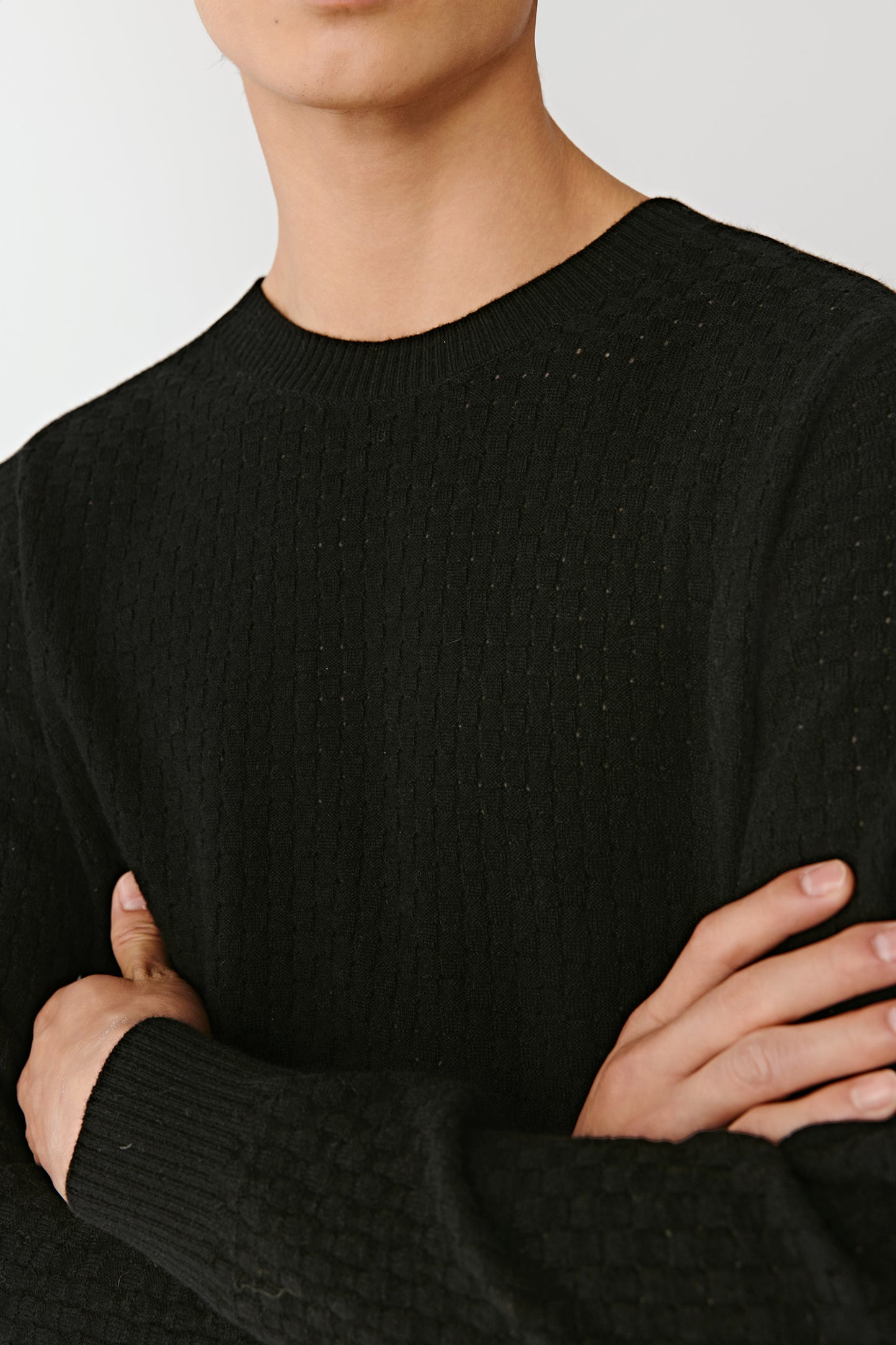 Close-up of the black wool pullover’s neckline and chest area, showing the even knit and soft texture.