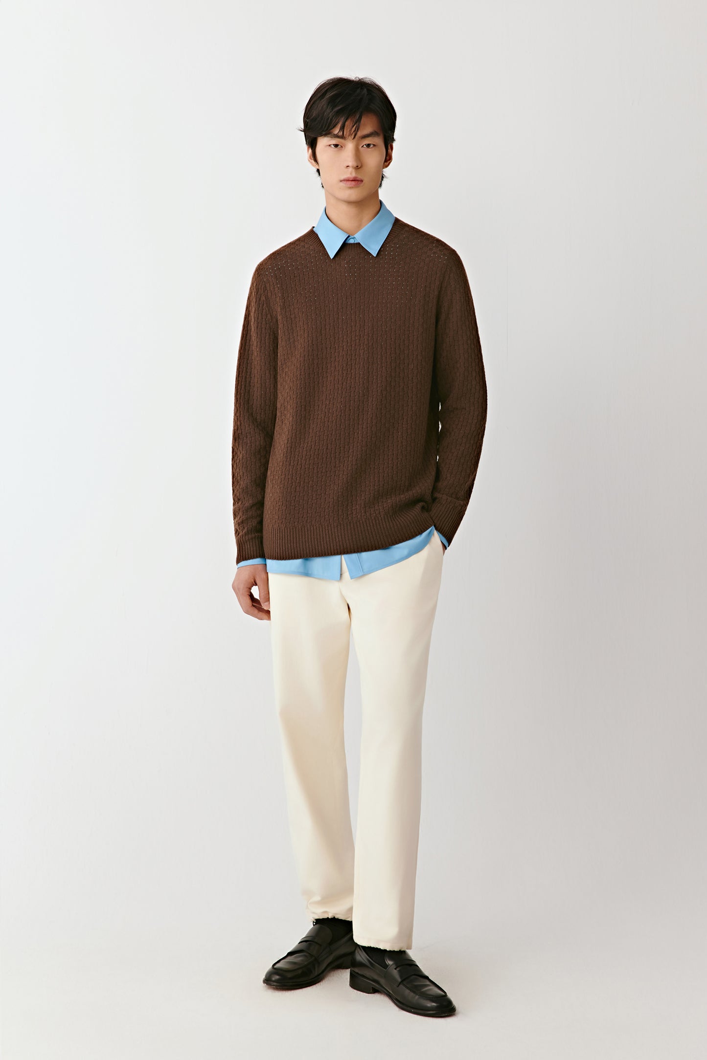 Full-length front view of a person wearing a dark brown wool and cashmere blend pullover with a crew neckline.