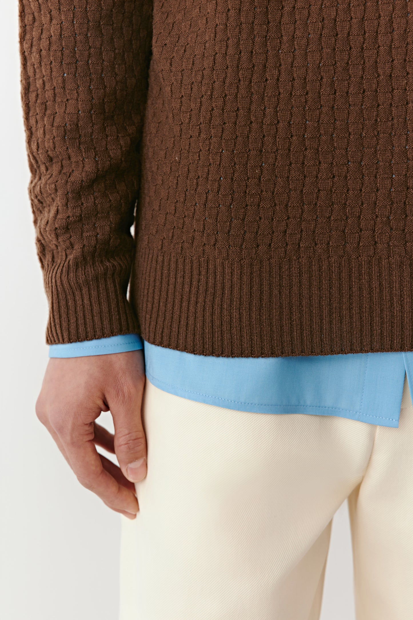Detail close-up of the sleeve and ribbed cuff of the brown wool pullover.
