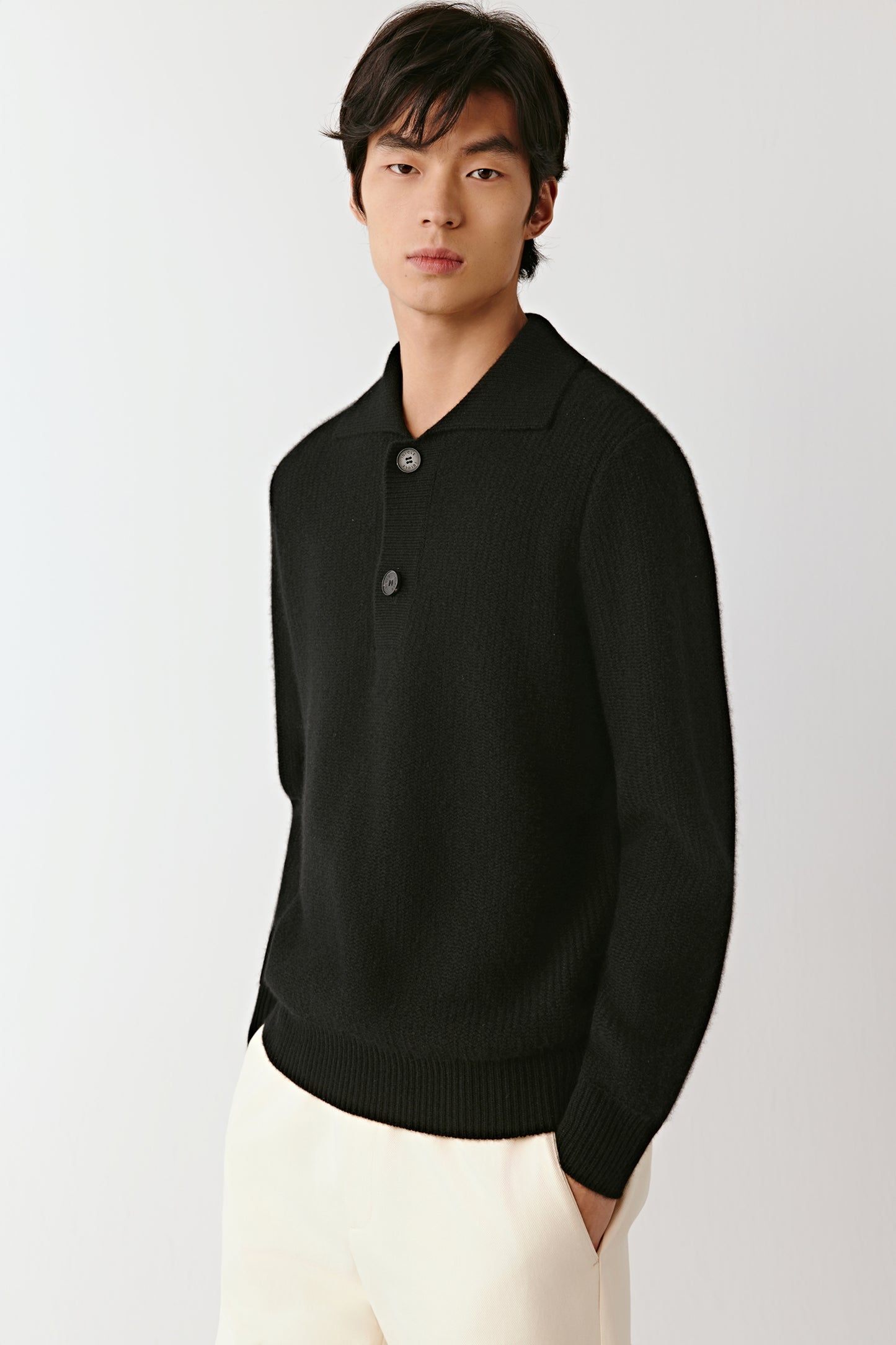 Three-quarter view of the black cashmere polo sweater, highlighting the soft knit, polo collar, and clean silhouette.