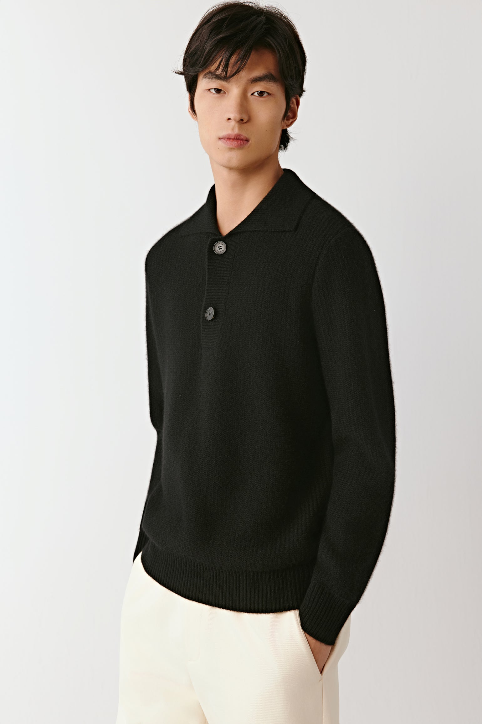 Three-quarter view of the black cashmere polo sweater, highlighting the soft knit, polo collar, and clean silhouette.
