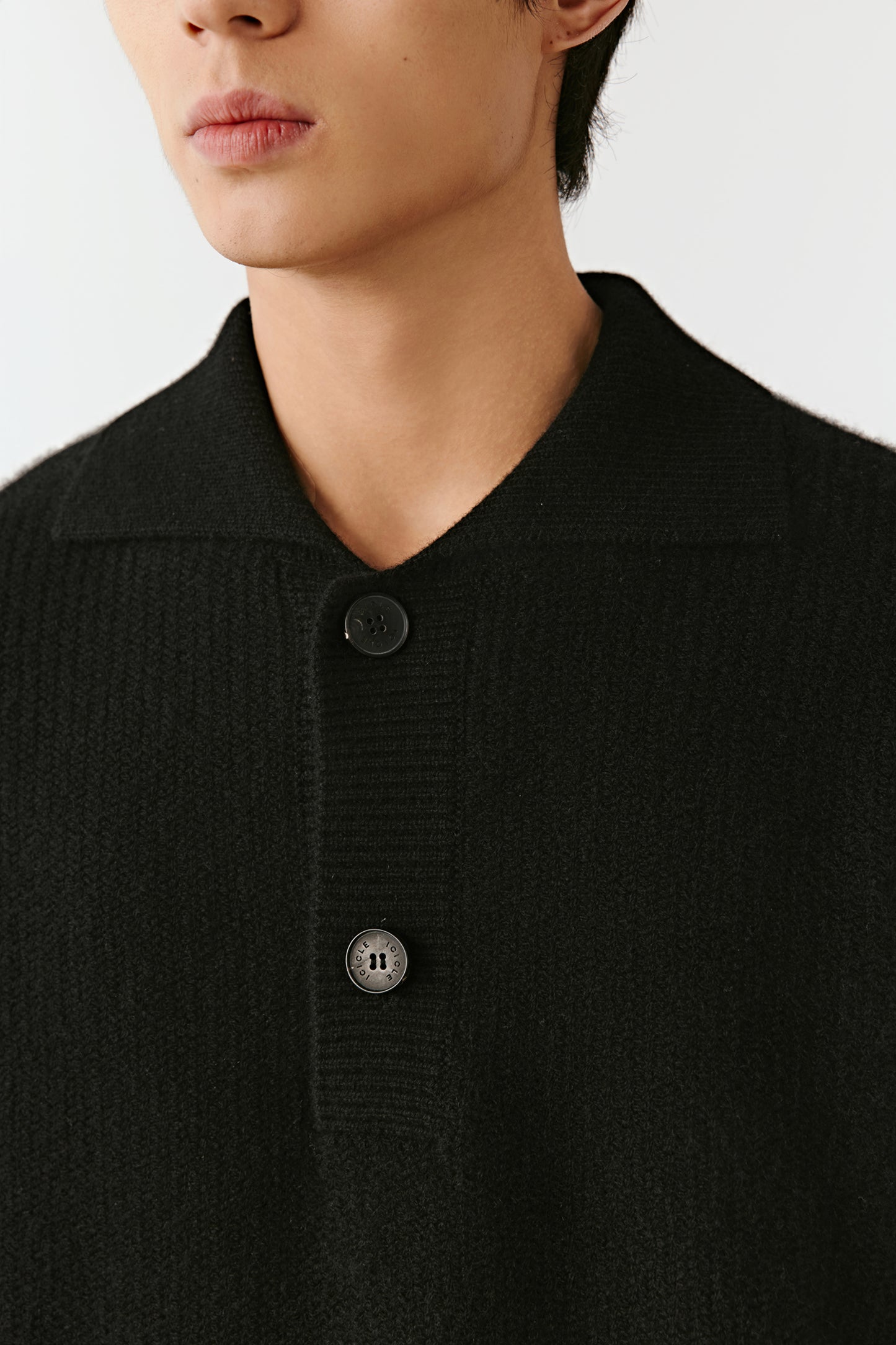 Close-up of the cashmere polo sweater’s collar and buttoned placket, showing fine knit texture and detailing.