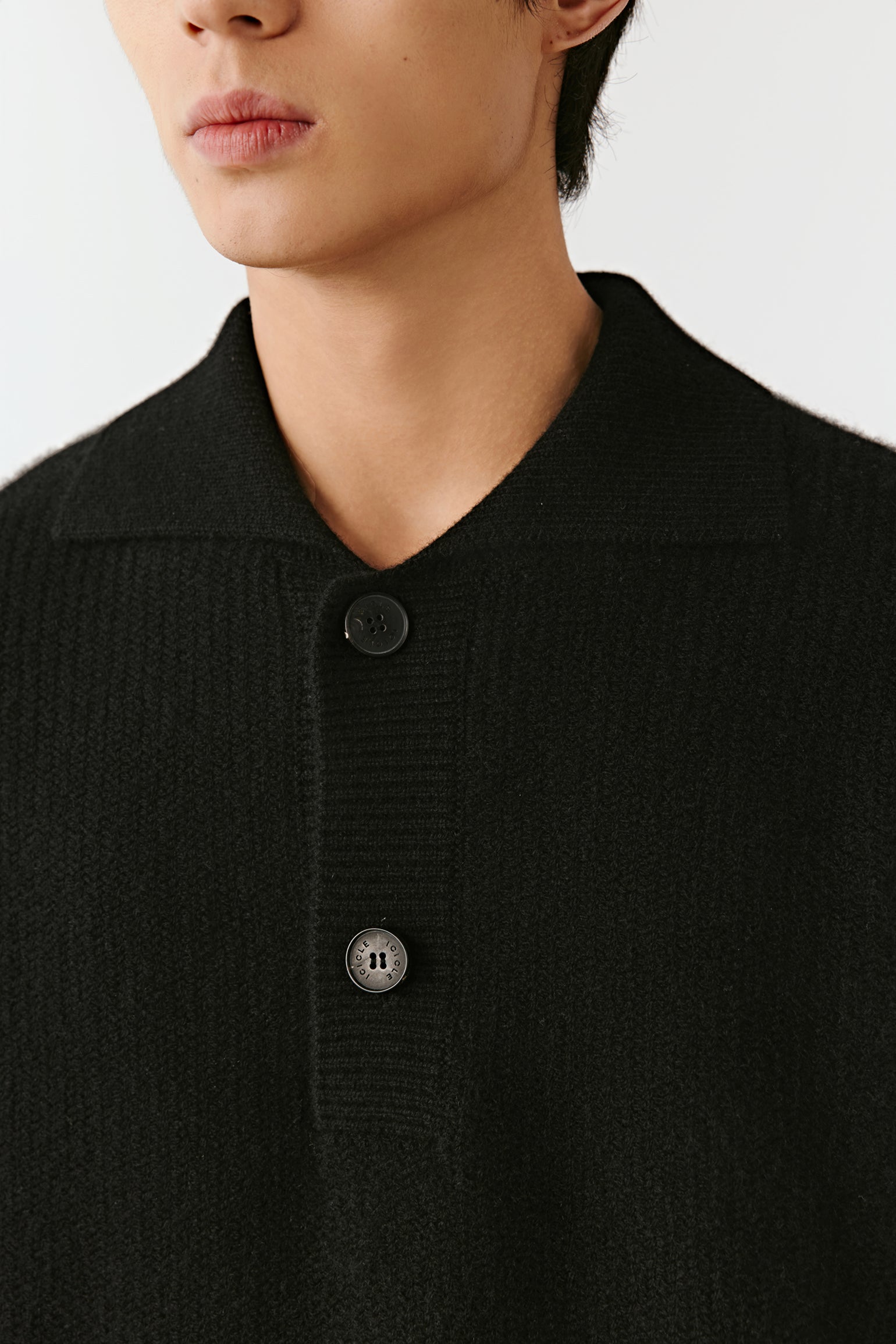 Close-up of the cashmere polo sweater’s collar and buttoned placket, showing fine knit texture and detailing.