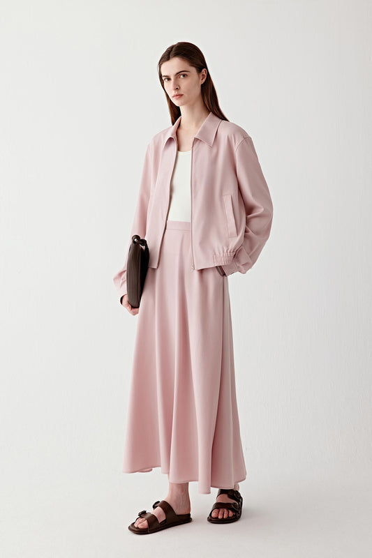 Full-length front view of a long soft pink wool twill skirt with a high waist and fluid, elongated silhouette, worn with flat sandals.