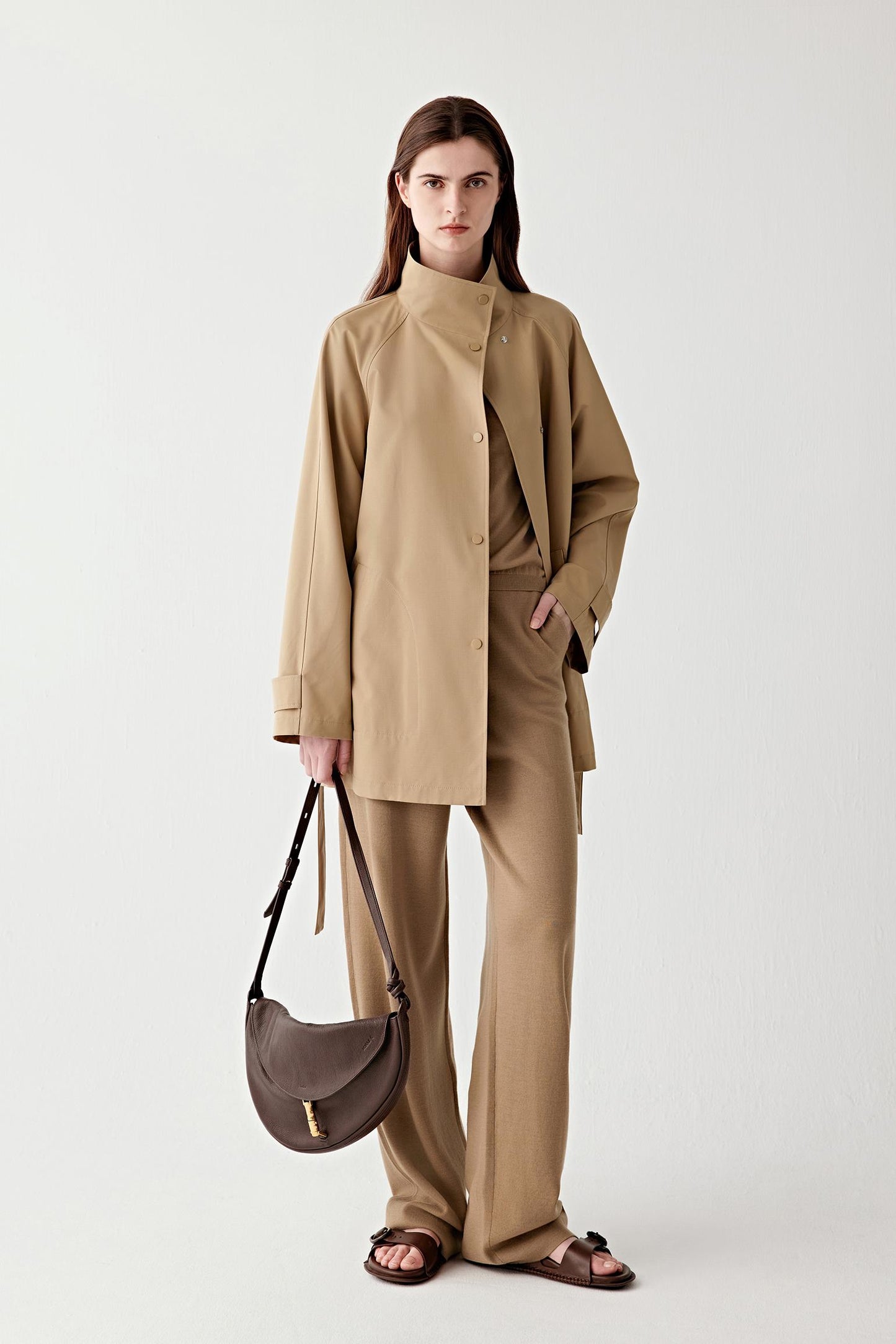 Woman wearing a short camel wool trench coat with matching trousers, full-length front view.