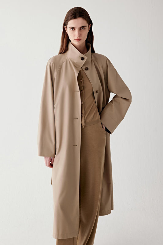 Three-quarter front view highlighting the clean lapels, relaxed tailoring, and soft structure of the trench coat.