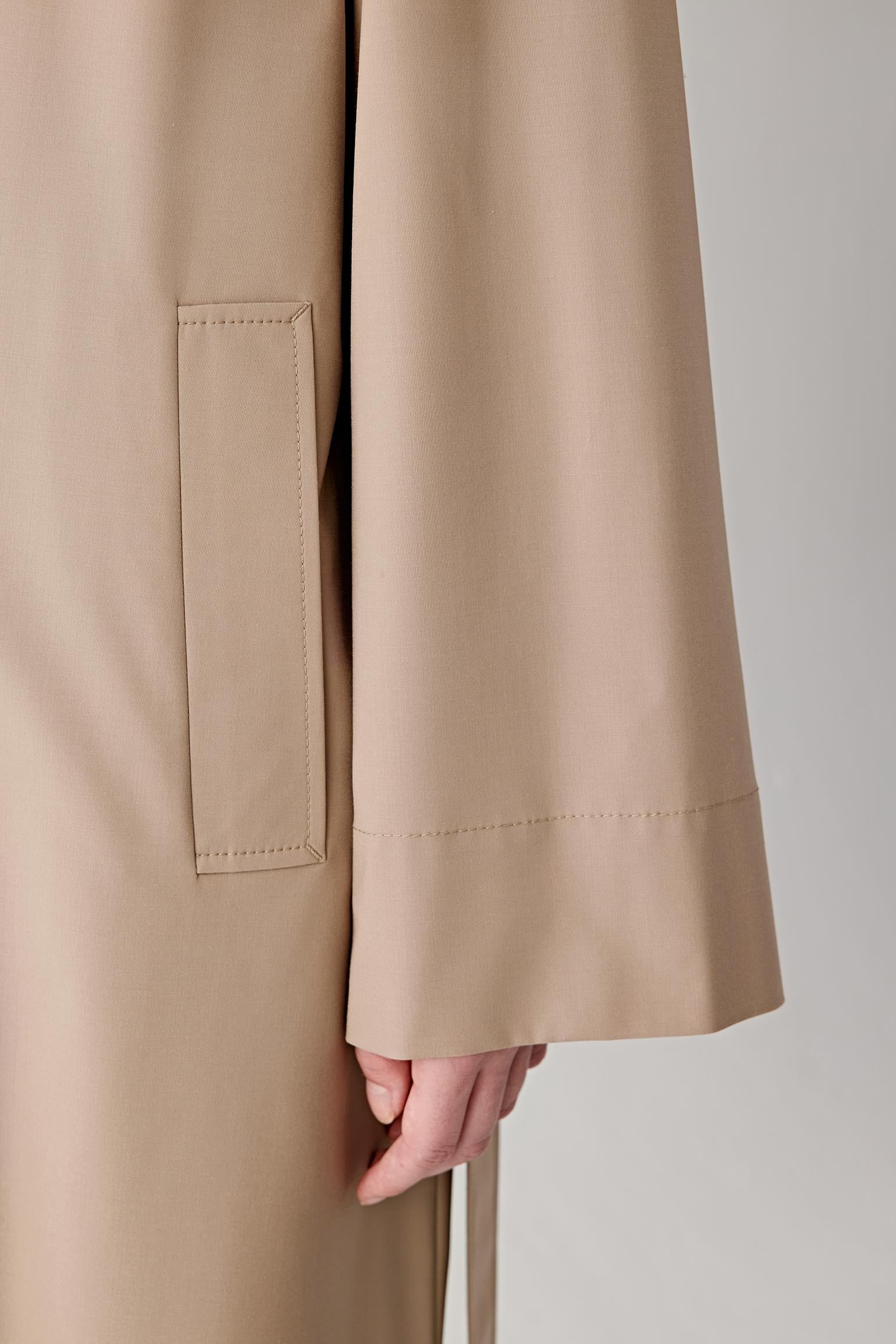 Close-up detail of the button fastening and fabric surface, showing refined finishing and tonal stitching.