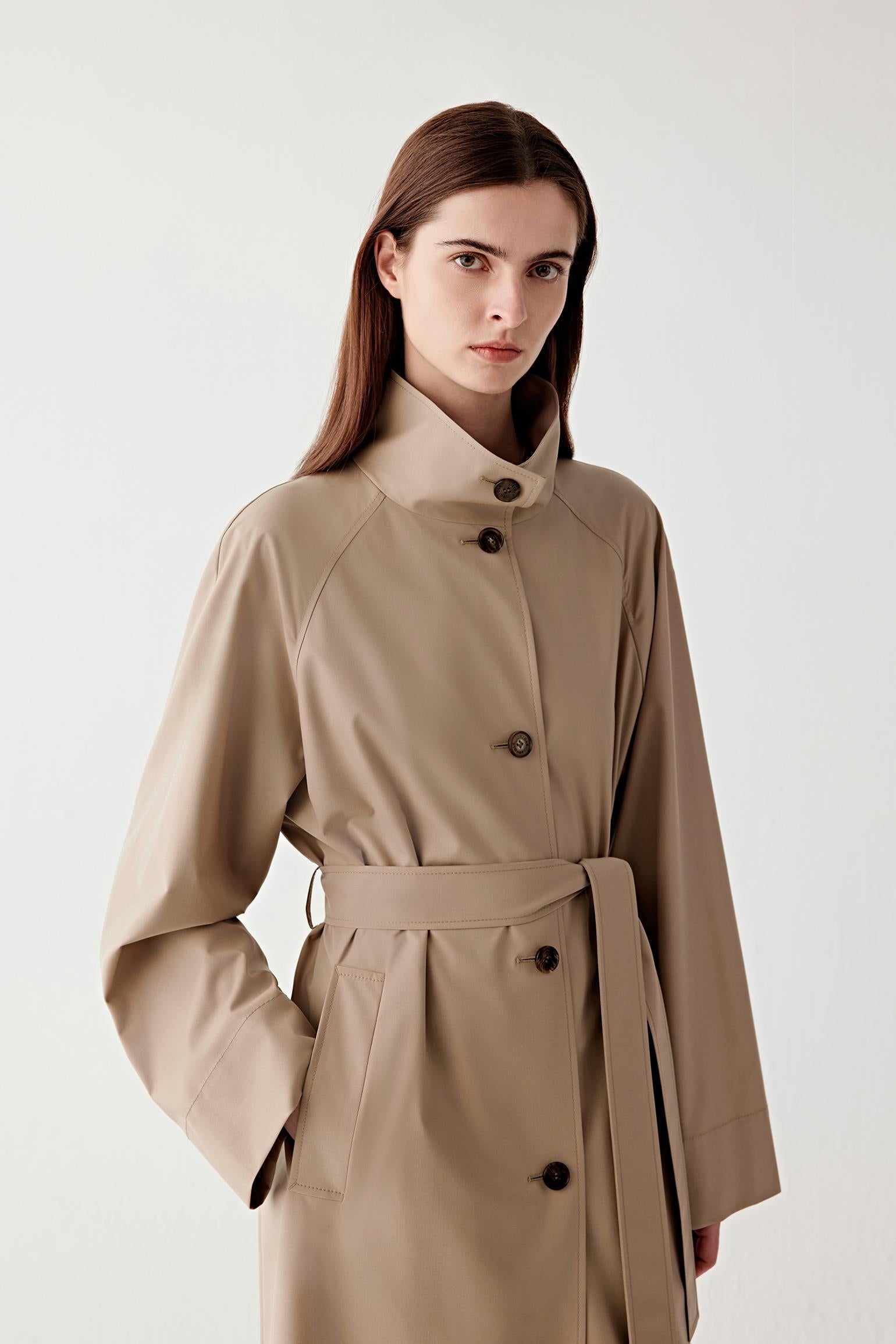 Close-up portrait view focusing on the upper body, collar, and smooth fabric texture of the trench coat.