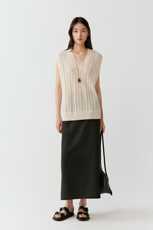 Full-length front view of a sleeveless cashmere and silk pullover with a V neckline, worn over a long skirt.