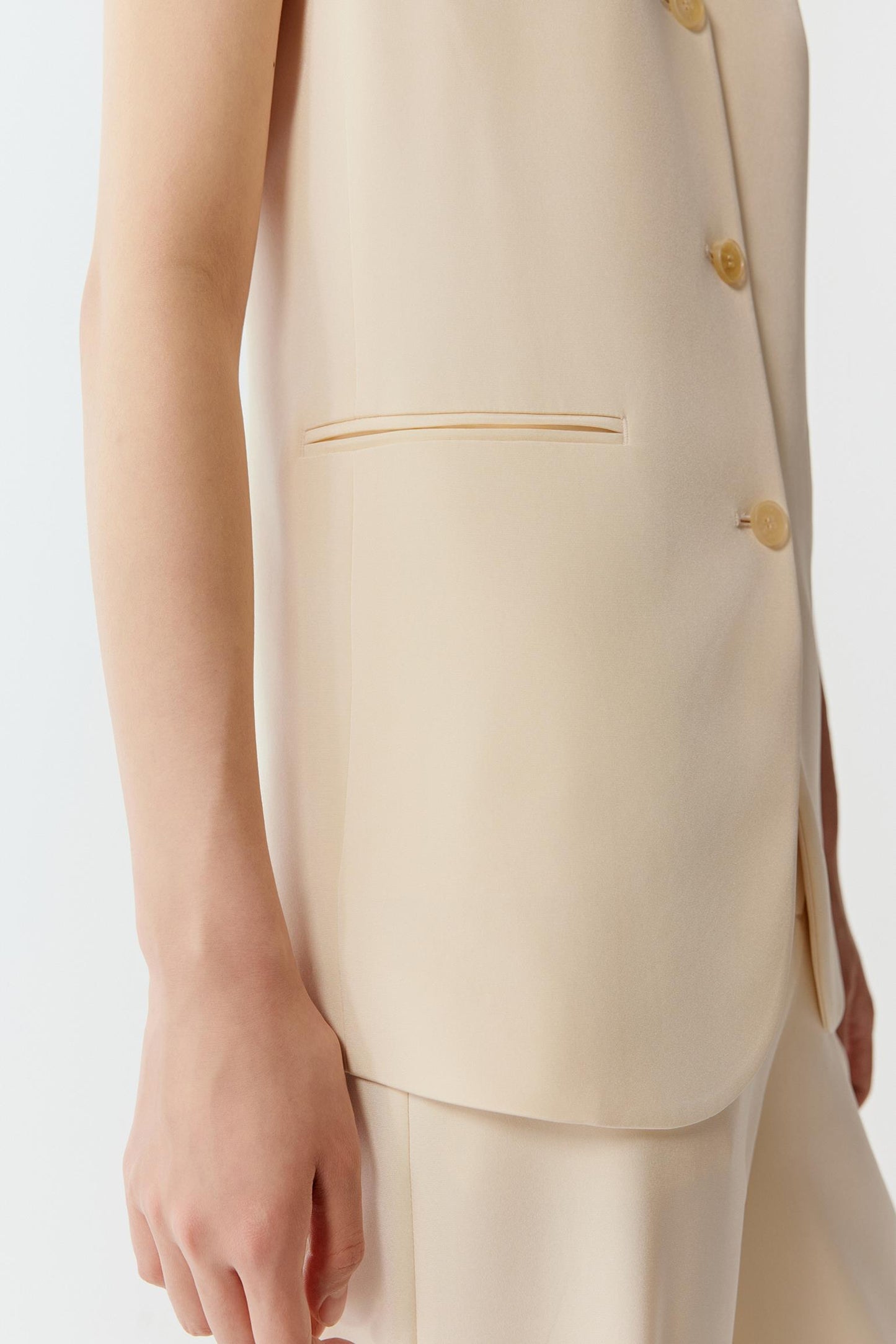 Close-up of the armhole and side body, showing the clean finishing, precise seam construction and dense, smooth crepe texture with a matte surface.