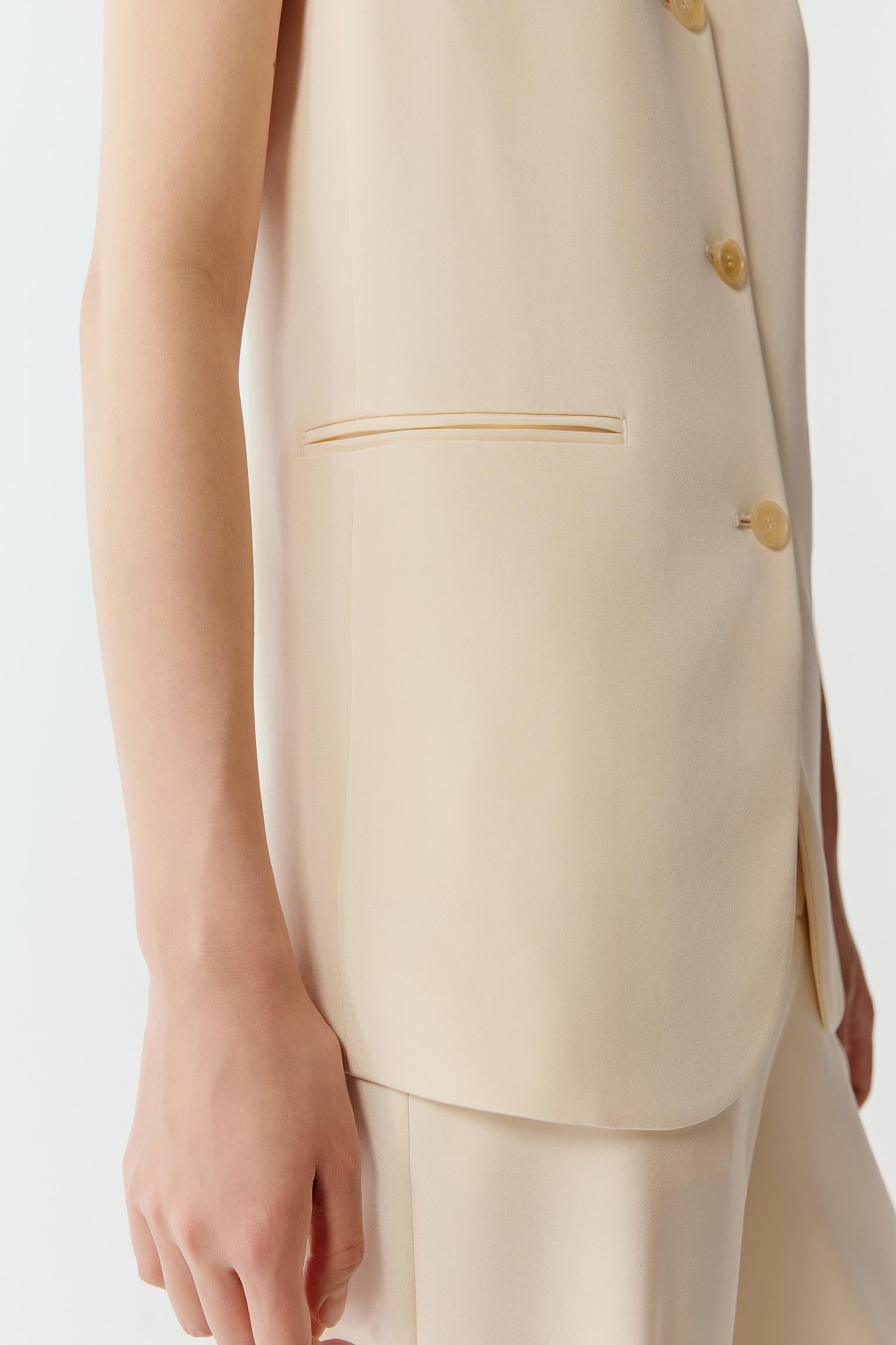 Close-up of the armhole and side body, showing the clean finishing, precise seam construction and dense, smooth crepe texture with a matte surface.