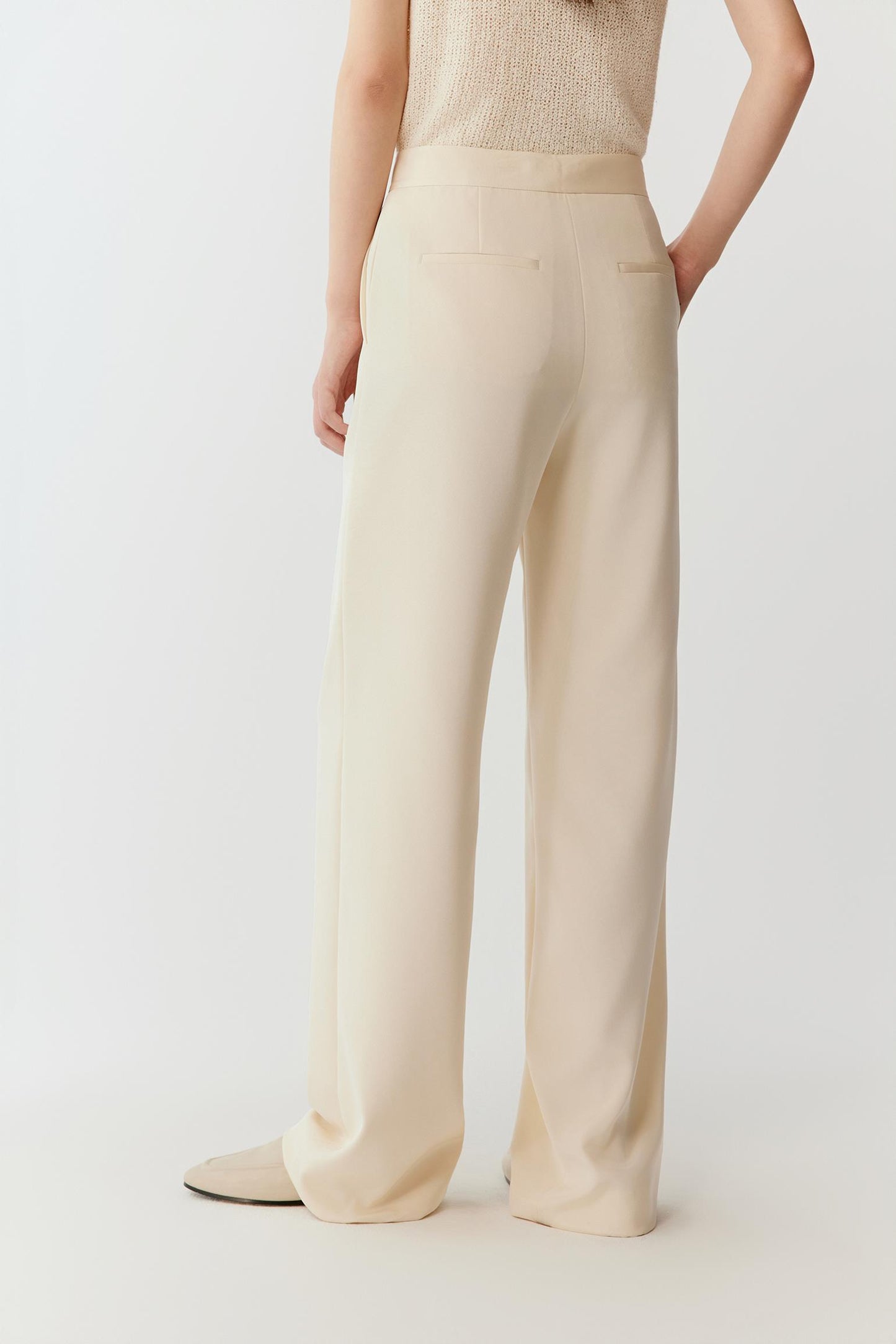 Back view emphasizing the vertical drape of the crepe, smooth line along the thigh and a subtly widened leg opening, creating a soft, elongated silhouette.