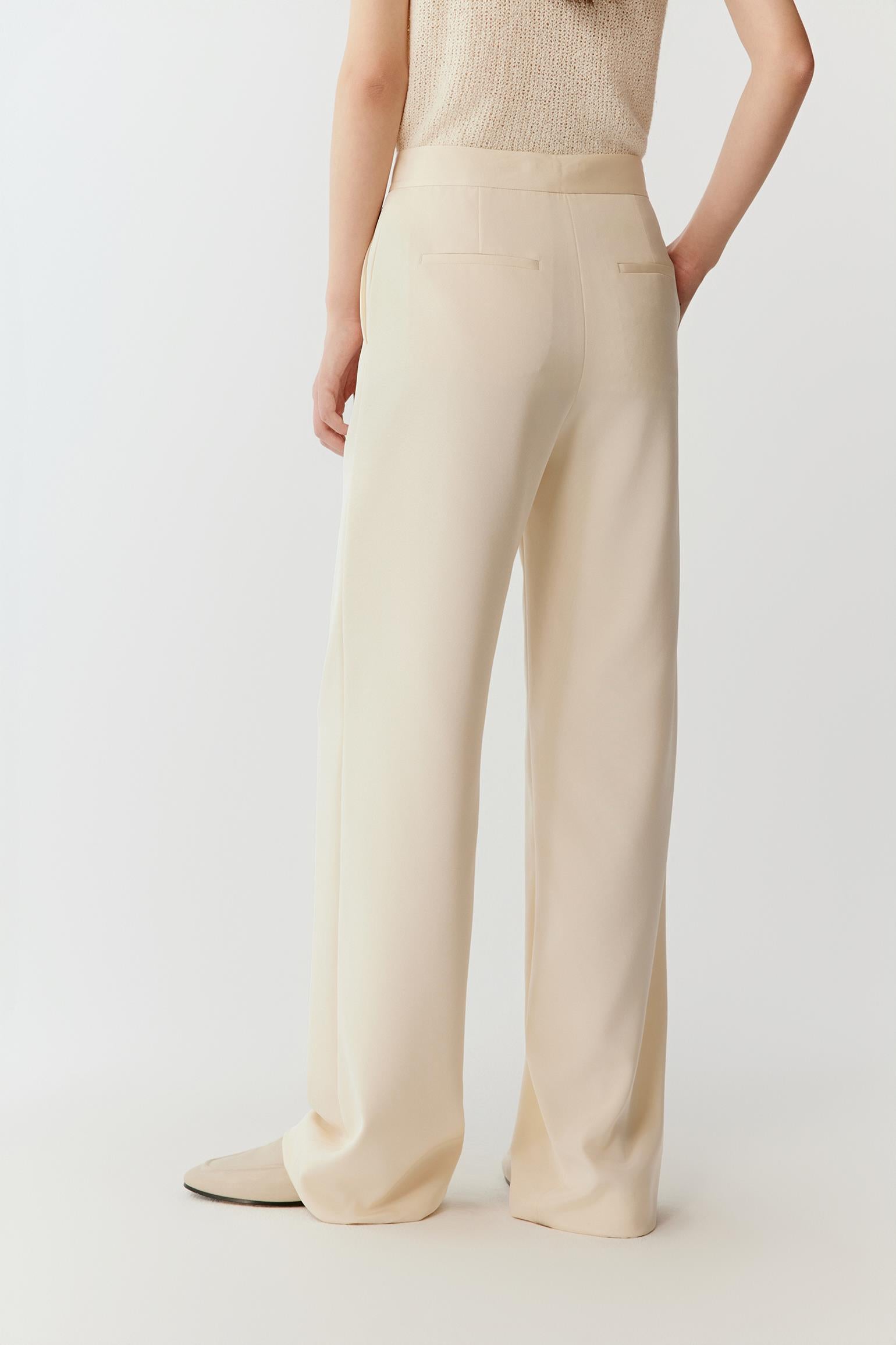 Back view emphasizing the vertical drape of the crepe, smooth line along the thigh and a subtly widened leg opening, creating a soft, elongated silhouette.