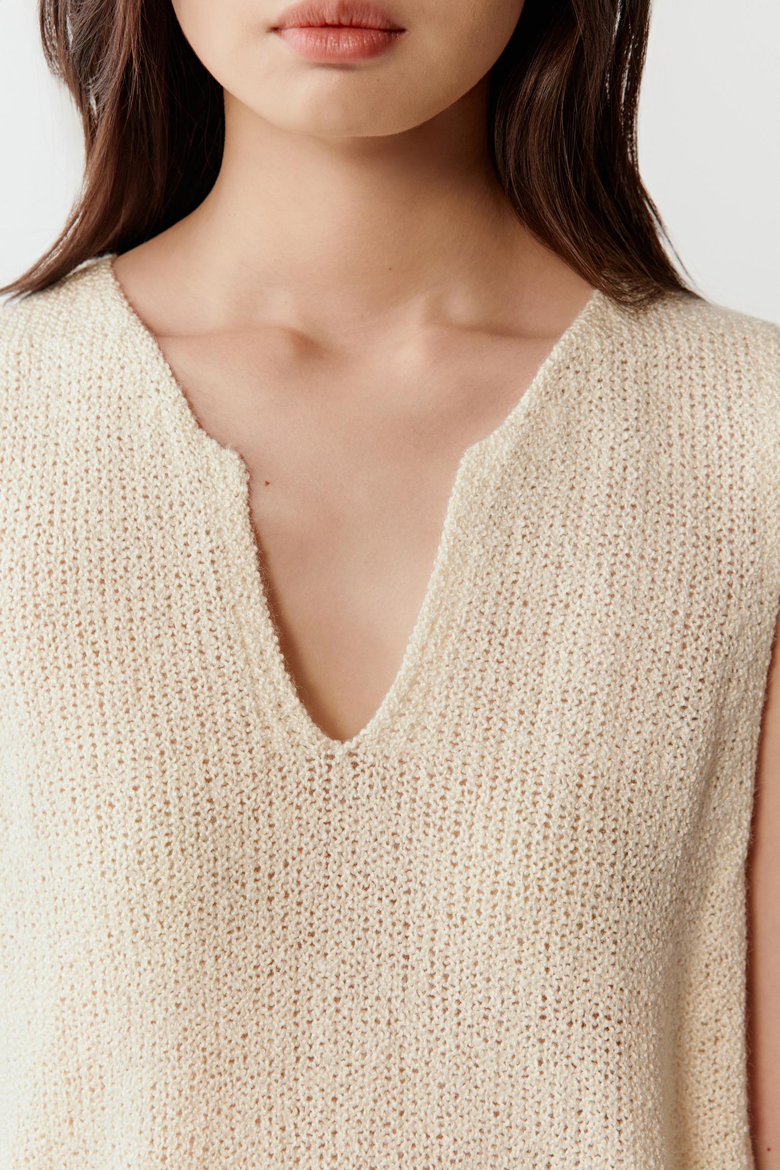 Close-up of the V-neckline and knit texture, highlighting the slightly irregular surface and soft finish of the silk yarn.
