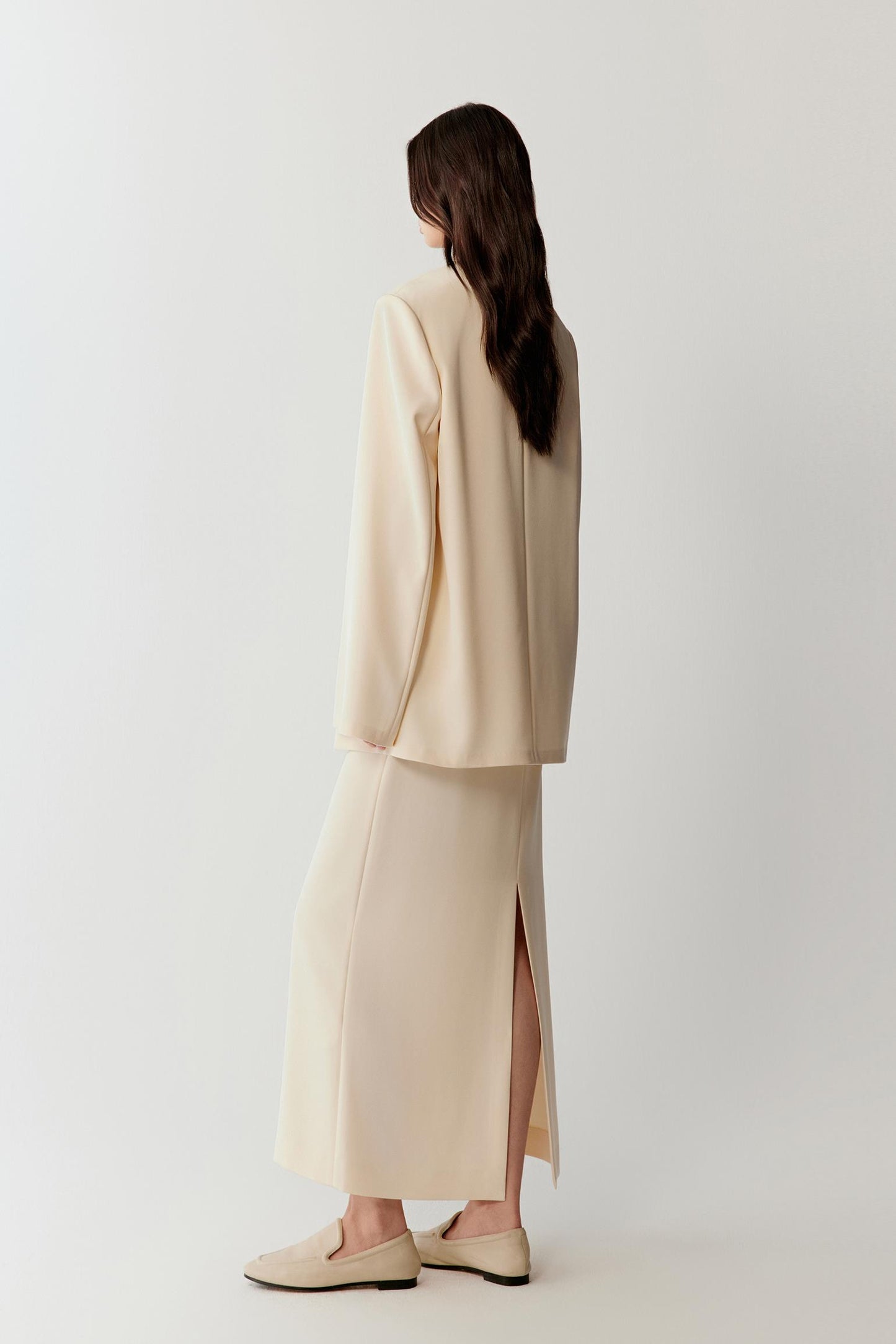 Side view emphasizing the length of the blazer, straight cut and smooth drape along the body.