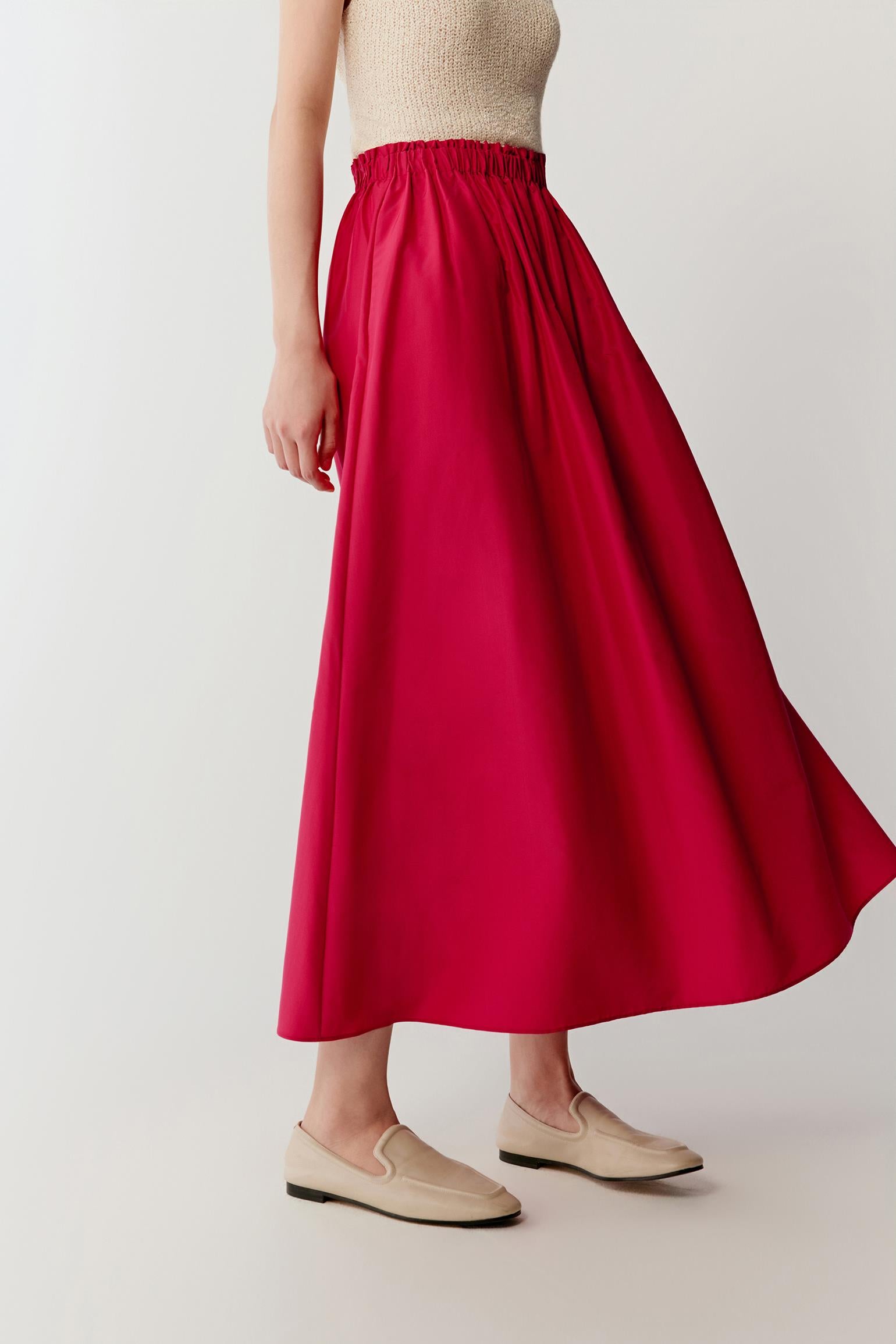 Three-quarter or back-angled view capturing movement, emphasizing how the skirt opens and shifts with motion, with soft folds forming across the surface and the length enhancing fluidity