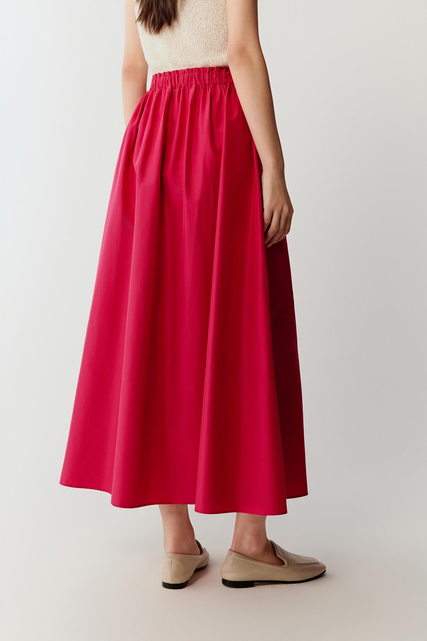 Side view showing the profile of the skirt, highlighting the fullness, rounded volume and the sculptural quality of the taffeta, with the fabric maintaining a controlled drape and structured fall