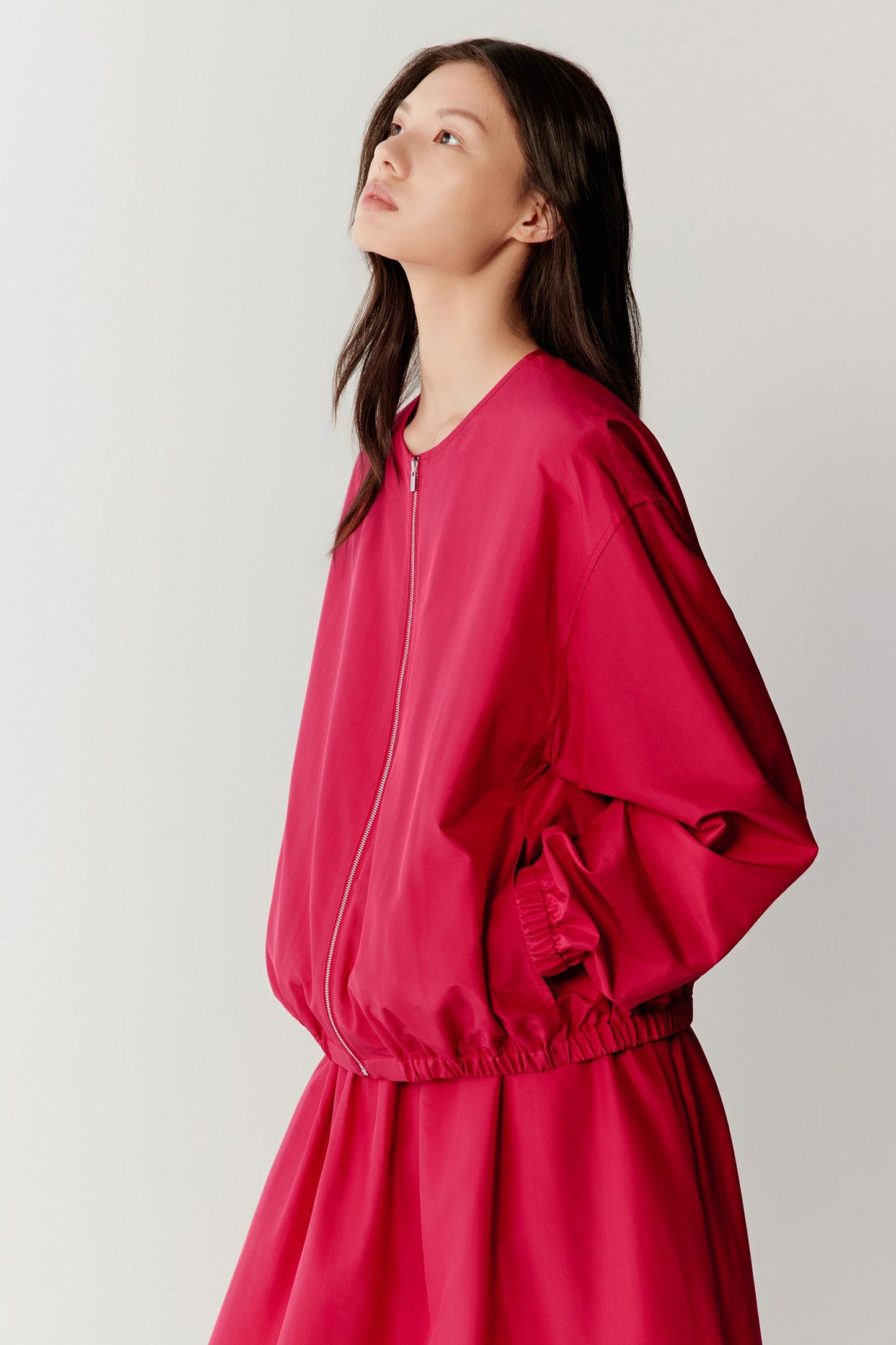 Side view focusing on the profile, emphasizing the volume through the sleeves, the gathered effect at the cuffs and hem, and the sculptural quality of the fabric as it extends away from the body