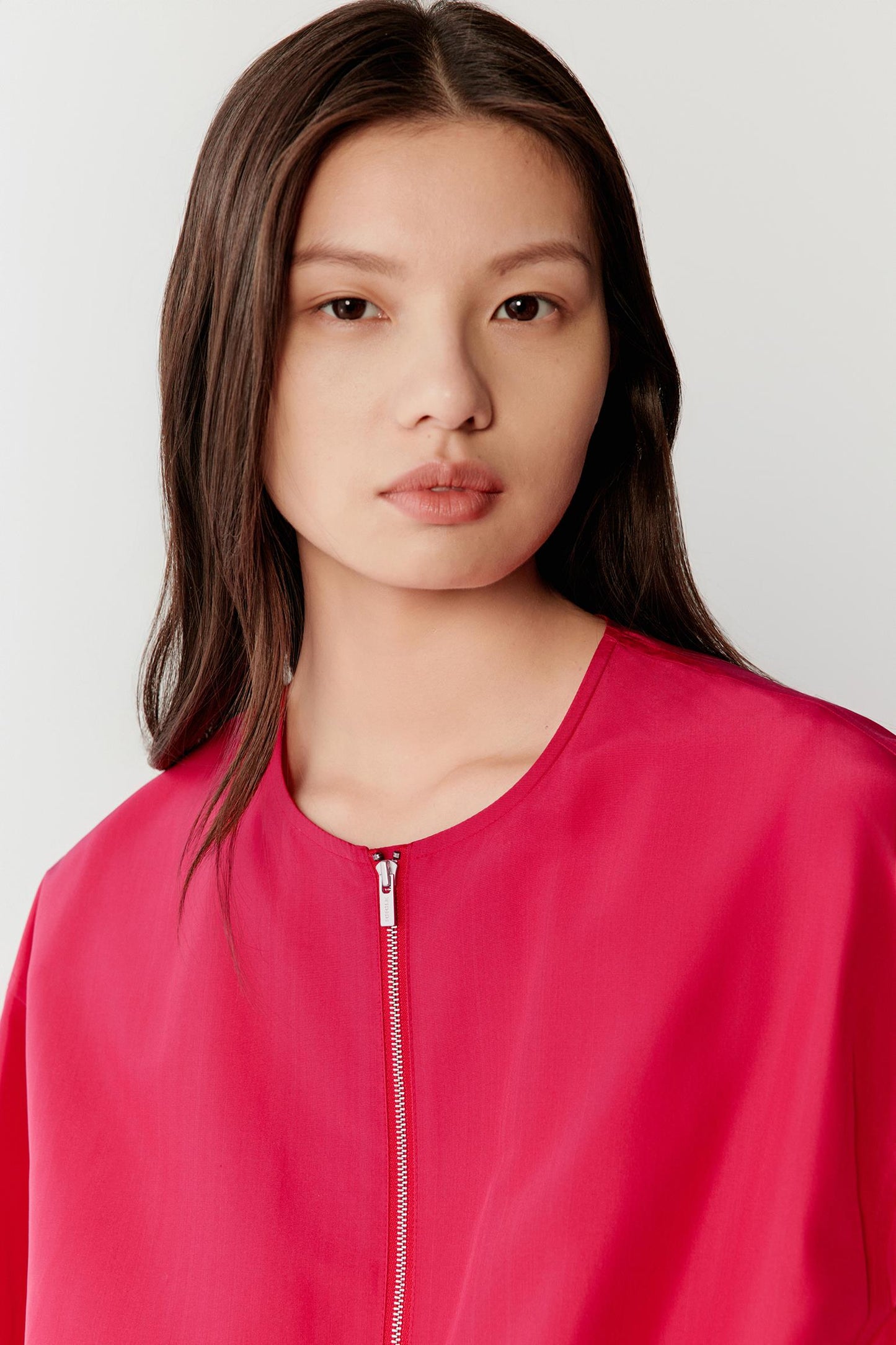 Close-up portrait focusing on the neckline and upper chest, detailing the round neckline, zip fastening and the smooth, slightly lustrous surface of silk taffeta, with a compact weave and clean finishing