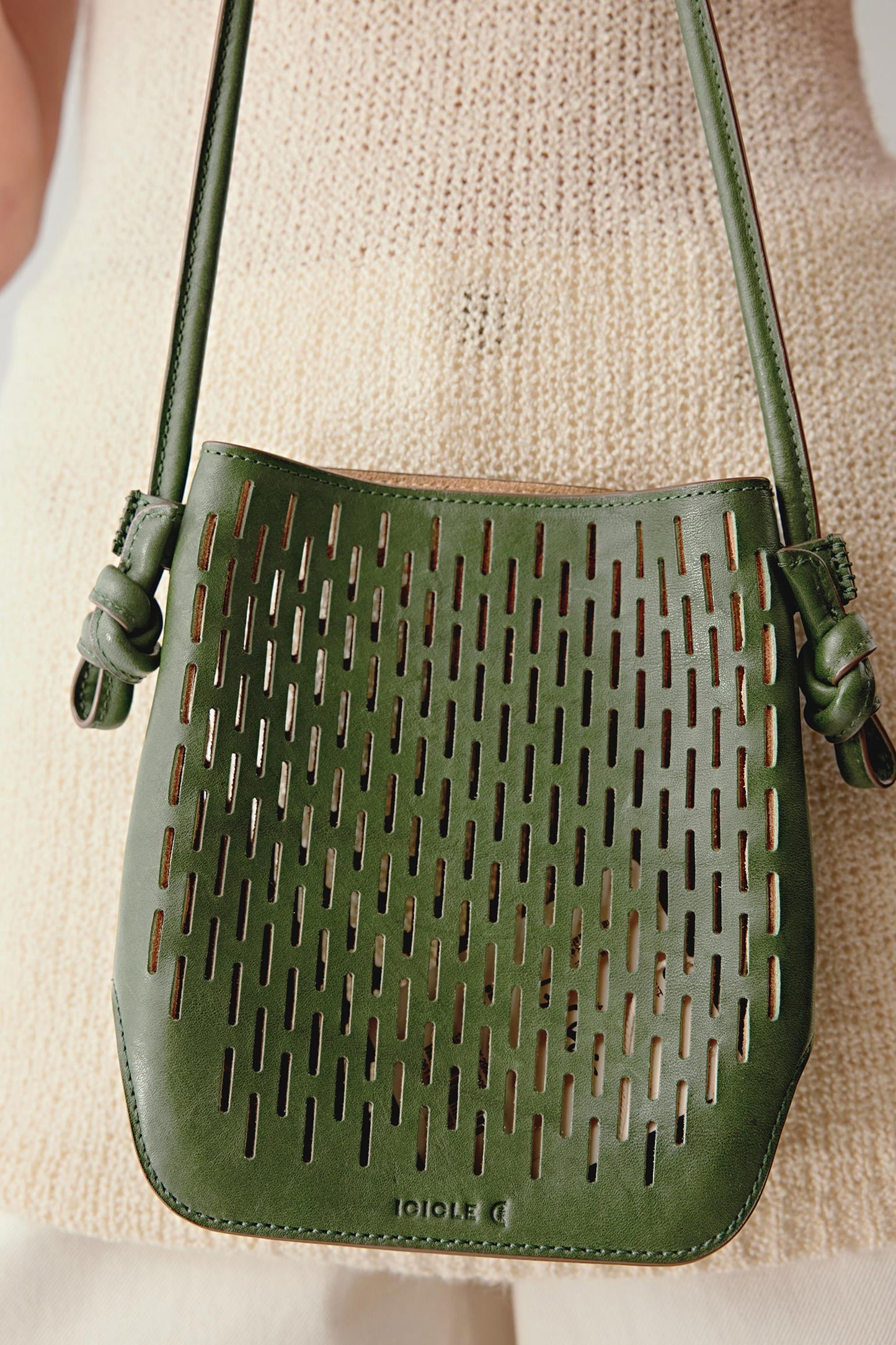 Front view of the khaki green perforated leather crossbody bag, highlighting the regular mesh pattern, flat base and structured silhouette.