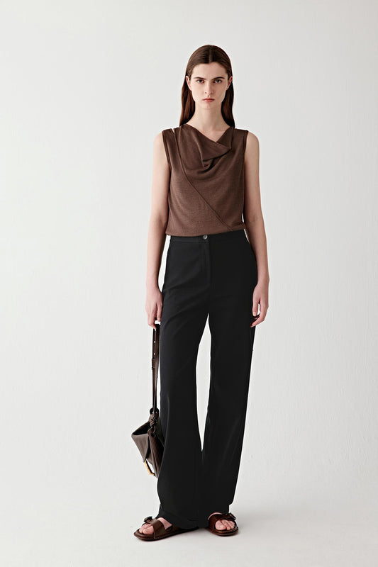 Full-length front view showing the top styled with straight black trousers, emphasizing the overall proportions, the way the fabric follows the upper body and falls loosely at the waist, and the contrast between the fluid top and the more structured trousers