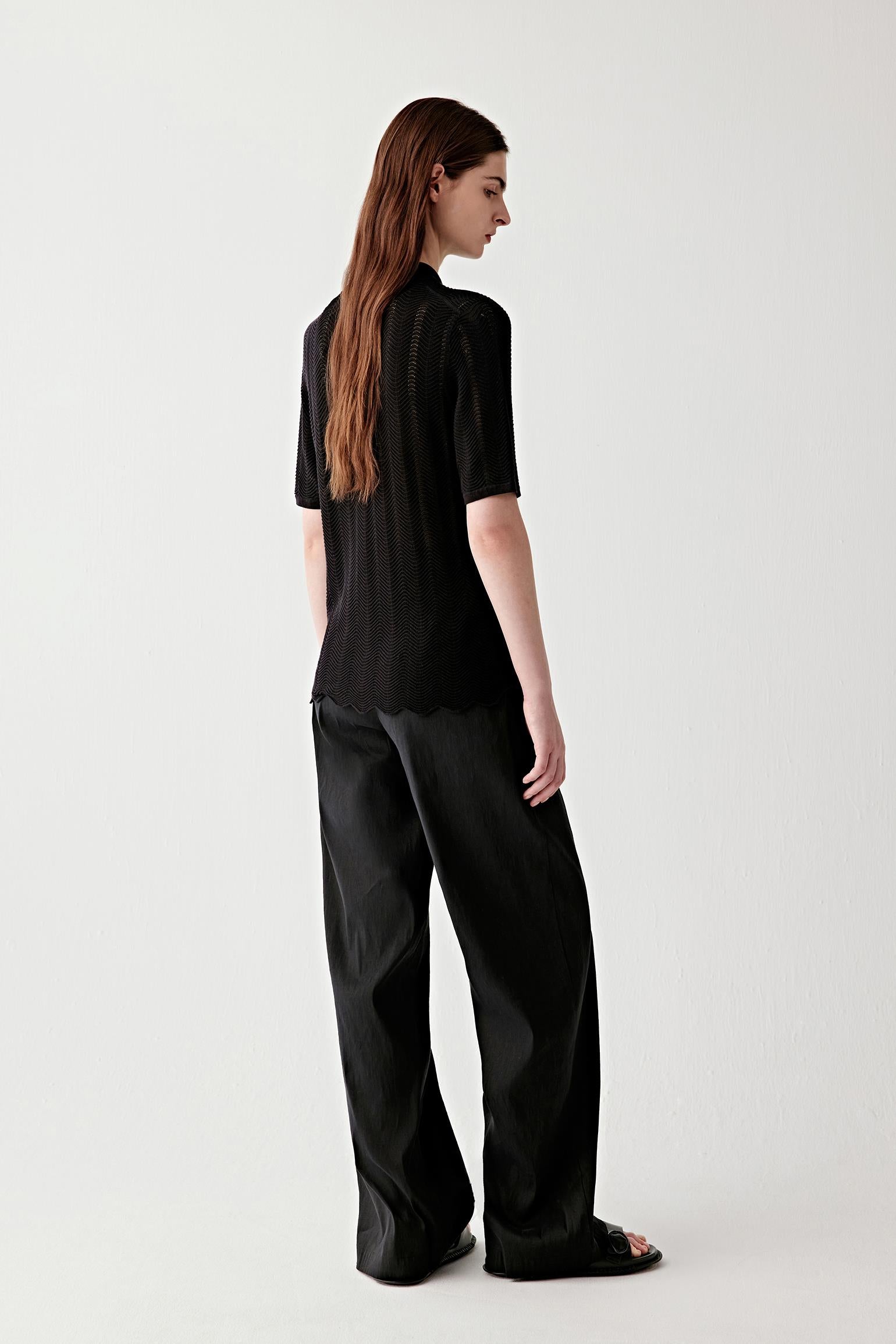 Full-length side view highlighting the vertical fall of the garment, the relaxed fit through the body and sleeves, and the way the knit fabric follows the movement while maintaining a clean line