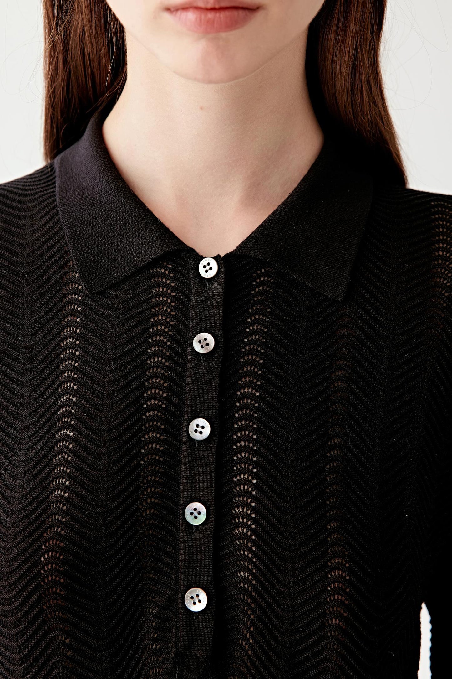 Close-up of the neckline and chest area, focusing on the polo collar, button placket construction and the fine openwork chevron pattern, revealing the texture and depth of the silk and cotton yarn blend