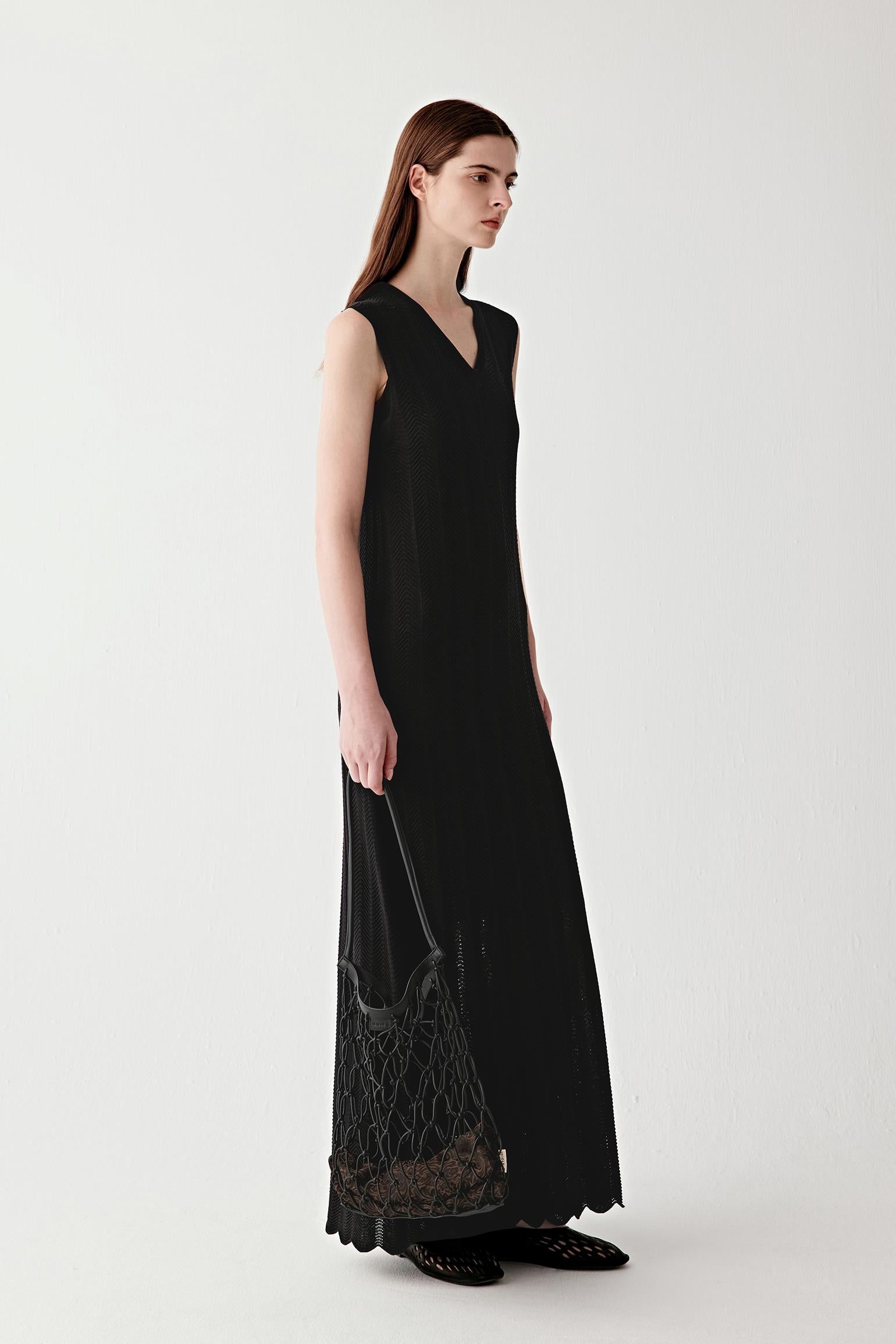 Three-quarter view showing the rear silhouette, emphasizing the clean lines, sleeveless construction and the fluid drape of the knit fabric as it moves away from the body