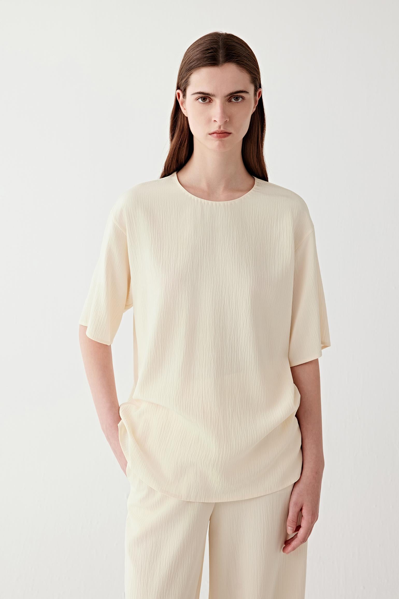 Mid-length front view focusing on the upper body, emphasizing the straight cut, short sleeve length and the way the fabric falls smoothly from the shoulders with a soft, continuous line