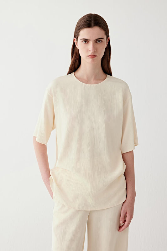 Mid-length front view focusing on the upper body, emphasizing the straight cut, short sleeve length and the way the fabric falls smoothly from the shoulders with a soft, continuous line