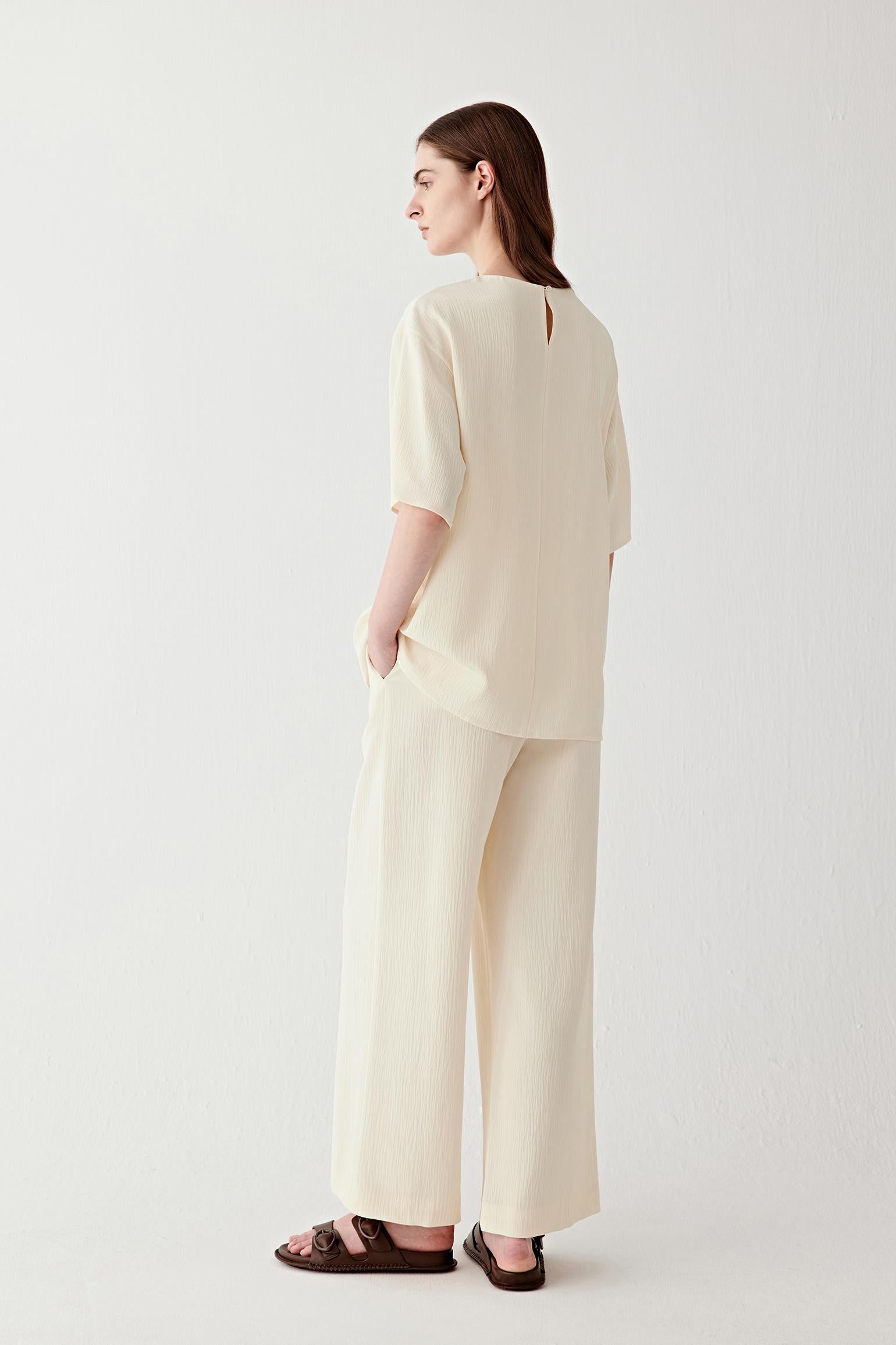 Full-length side view showing the blouse in profile, highlighting the fluid movement of the silk, the slightly loose fit through the body and the clean, uninterrupted silhouette