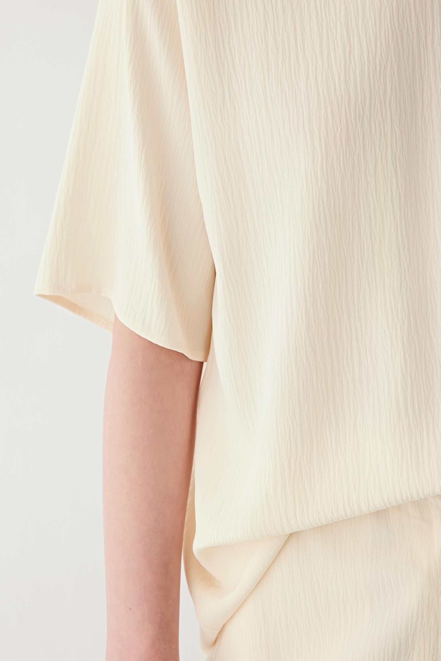 Close-up of the sleeve and side seam, highlighting the short sleeve construction, clean finishing and the lightweight structure of the fabric