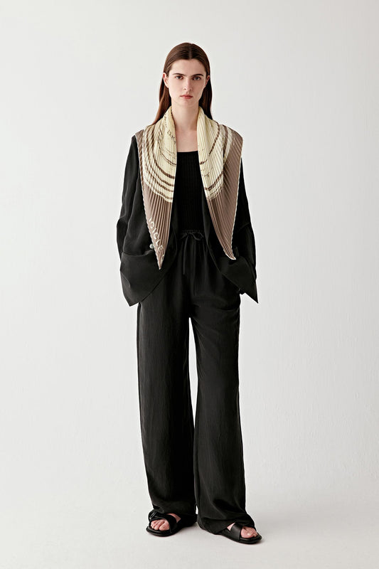 Full-length view of a natural fibre scarf worn over a dark tailored outfit, showing its length and fluid drape.