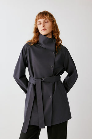 Three-quarter front view emphasizing the self-fabric belt, concealed fastening and fluid drape of the dense wool fabric.