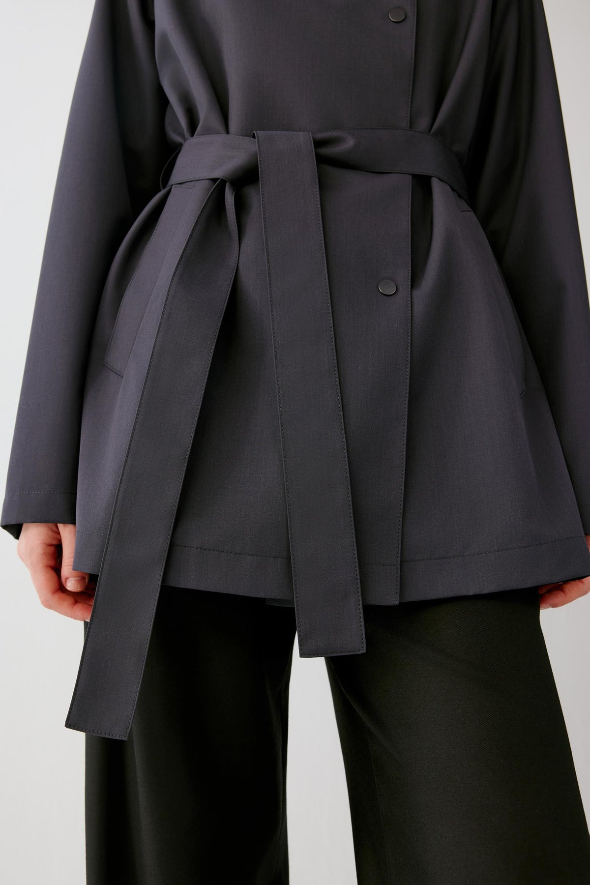 Close-up of the waist highlighting the self-fabric belt, covered buckle and clean construction of the trench coat.