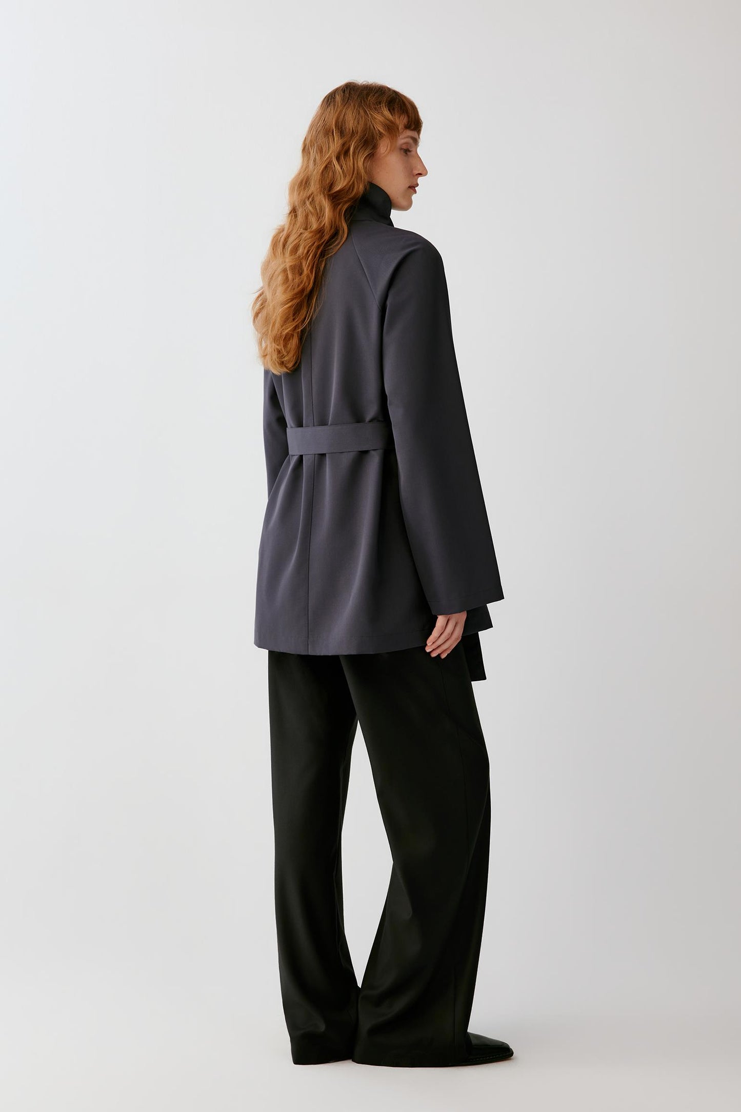 Back view highlighting the clean construction, long silhouette and smooth surface of the charcoal grey wool.