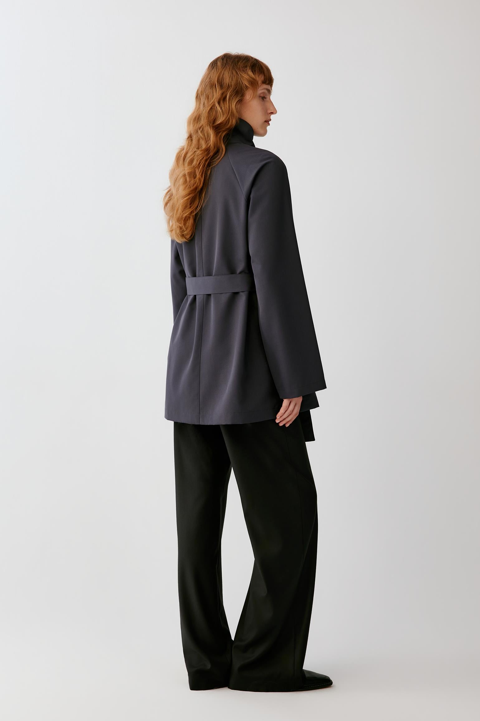 Back view highlighting the clean construction, long silhouette and smooth surface of the charcoal grey wool.