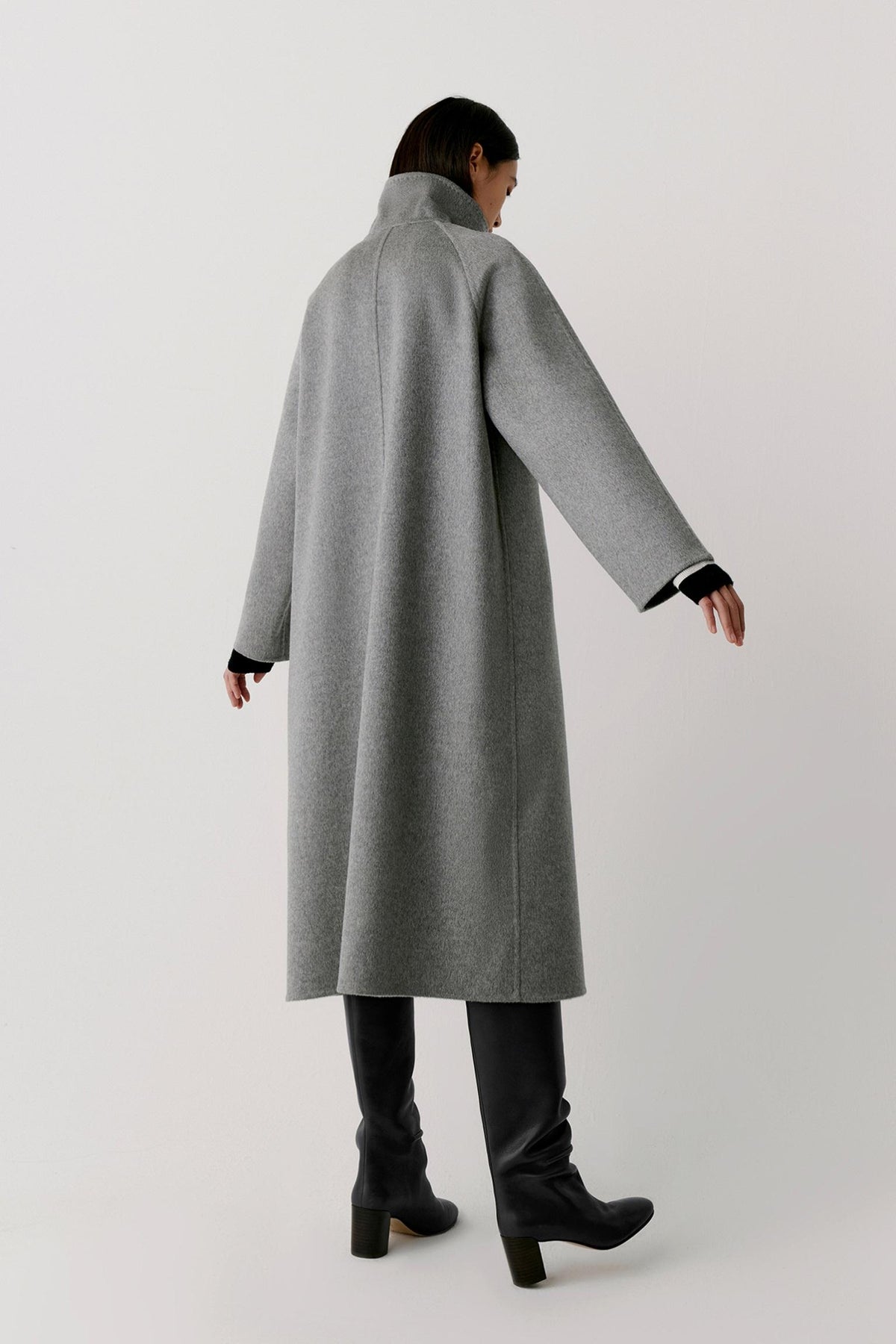 Back view of a woman wearing the grey melange double-face cashmere coat, showing the long silhouette, raglan sleeves and clean construction.