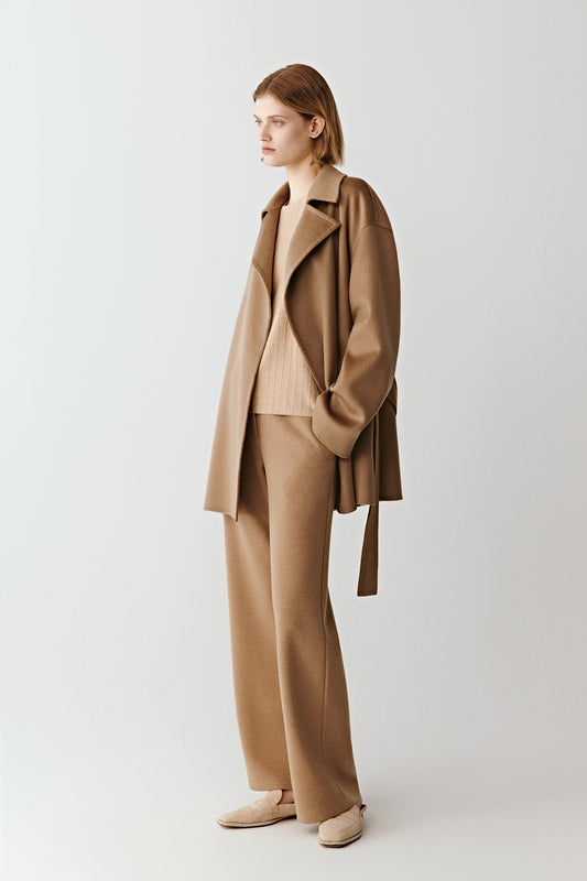 The model is shown in a relaxed stance, revealing the trousers’ fluid drape and the soft structure of the fabric.