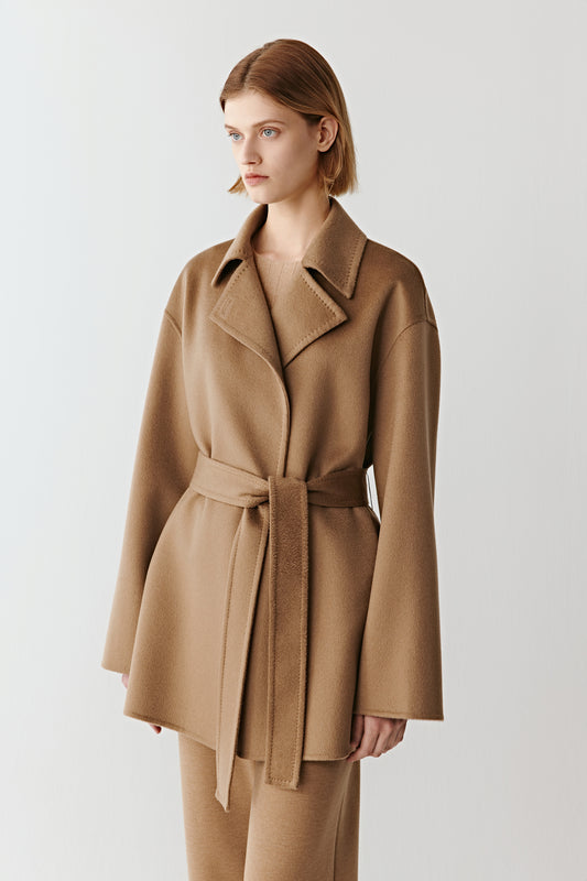Woman wearing a camel wool belted jacket styled with matching wide leg trousers on a light background
