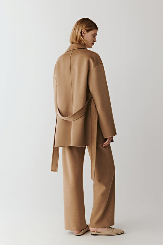 Back view of a camel wool belted jacket and matching trousers on a light background