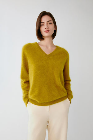 Front view of a woman wearing the mustard yellow cashmere pullover, highlighting the V-neck and fine-knit construction.