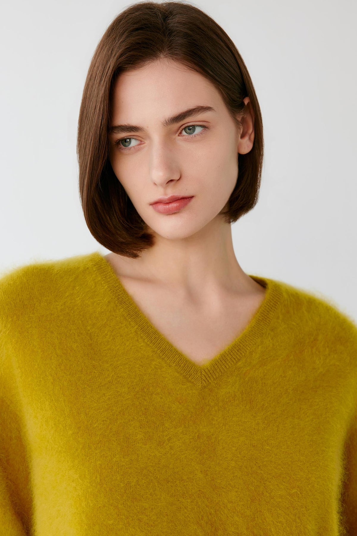 Front close-up highlighting the V-neck and fine-knit texture of the mustard yellow cashmere pullover.