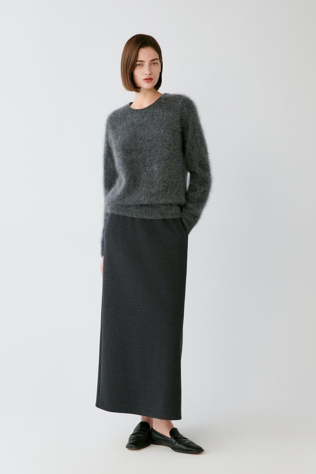 Front full-length view of a woman wearing the smoky grey cashmere pullover, highlighting the straight fit and long sleeves.
