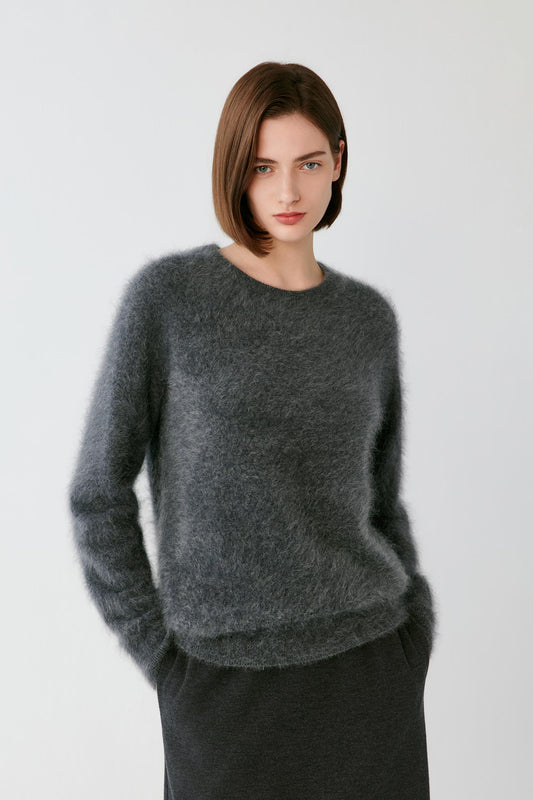 Front view of a woman wearing a smoky grey cashmere pullover, showing the round neckline, dropped shoulders and straight silhouette.