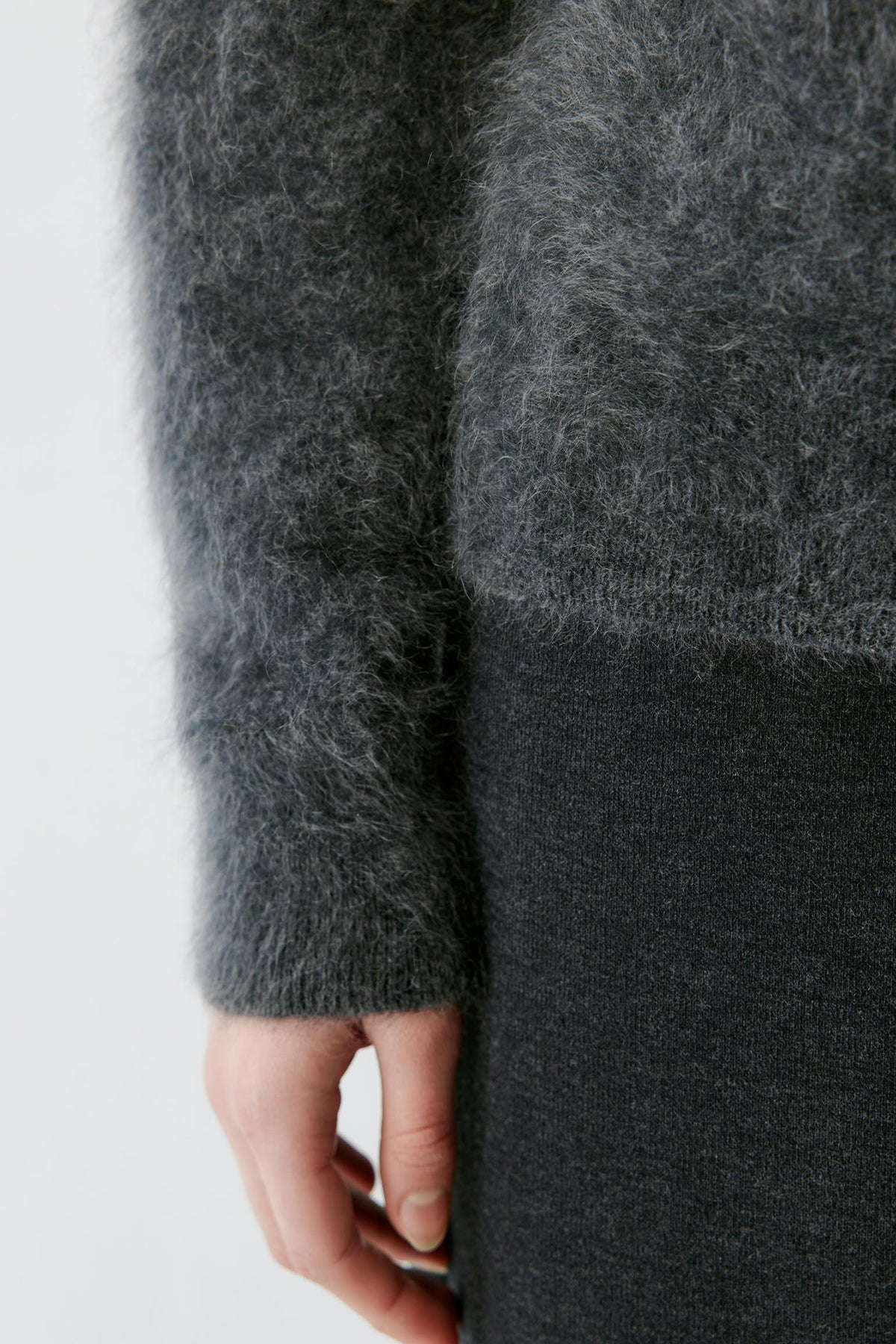 Close-up highlighting the ribbed cuff and brushed cashmere texture of the smoky grey pullover.